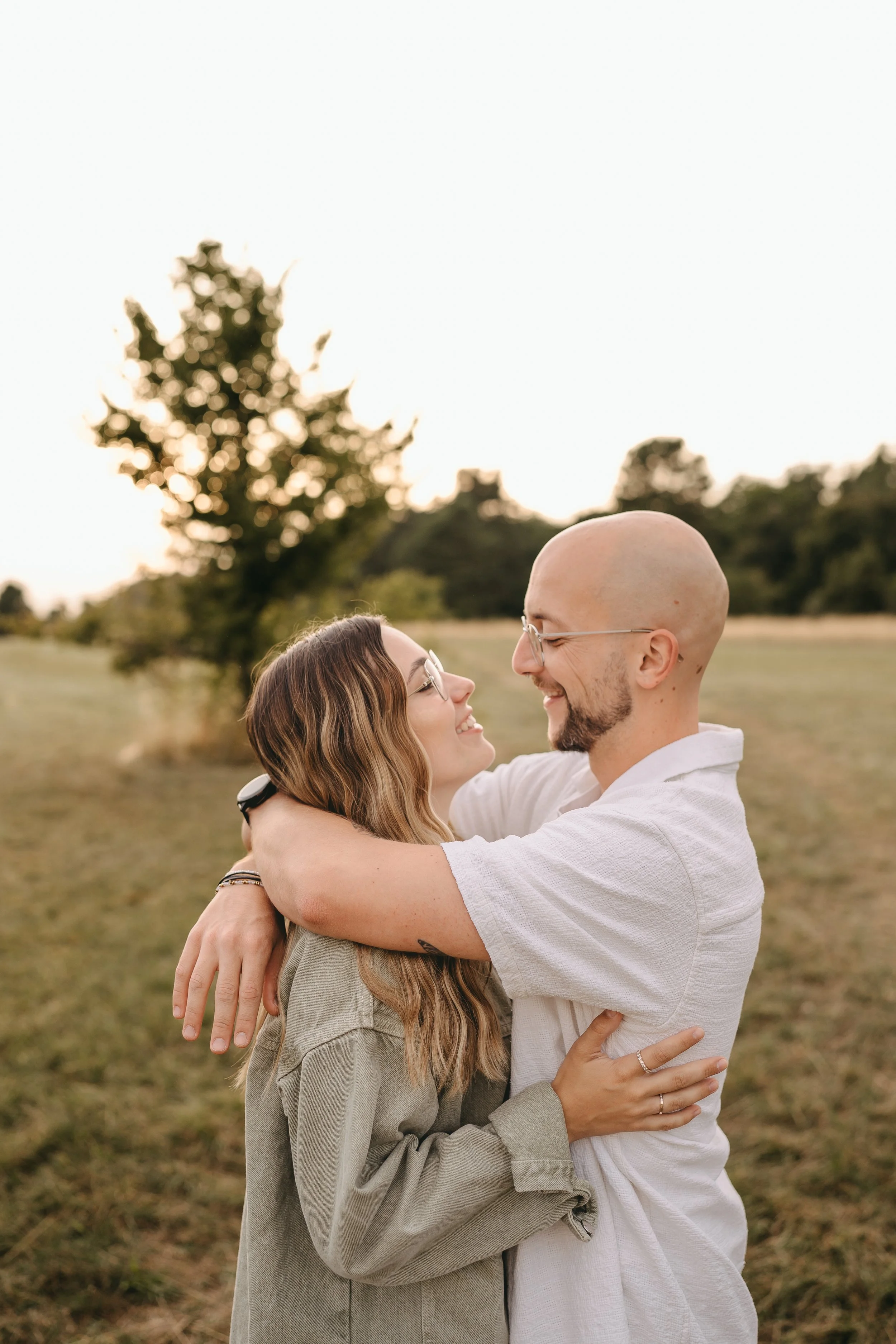 Ein Paar umarmt sich liebevoll im Freien bei Sonnenuntergang, lacht und sieht sich in die Augen.