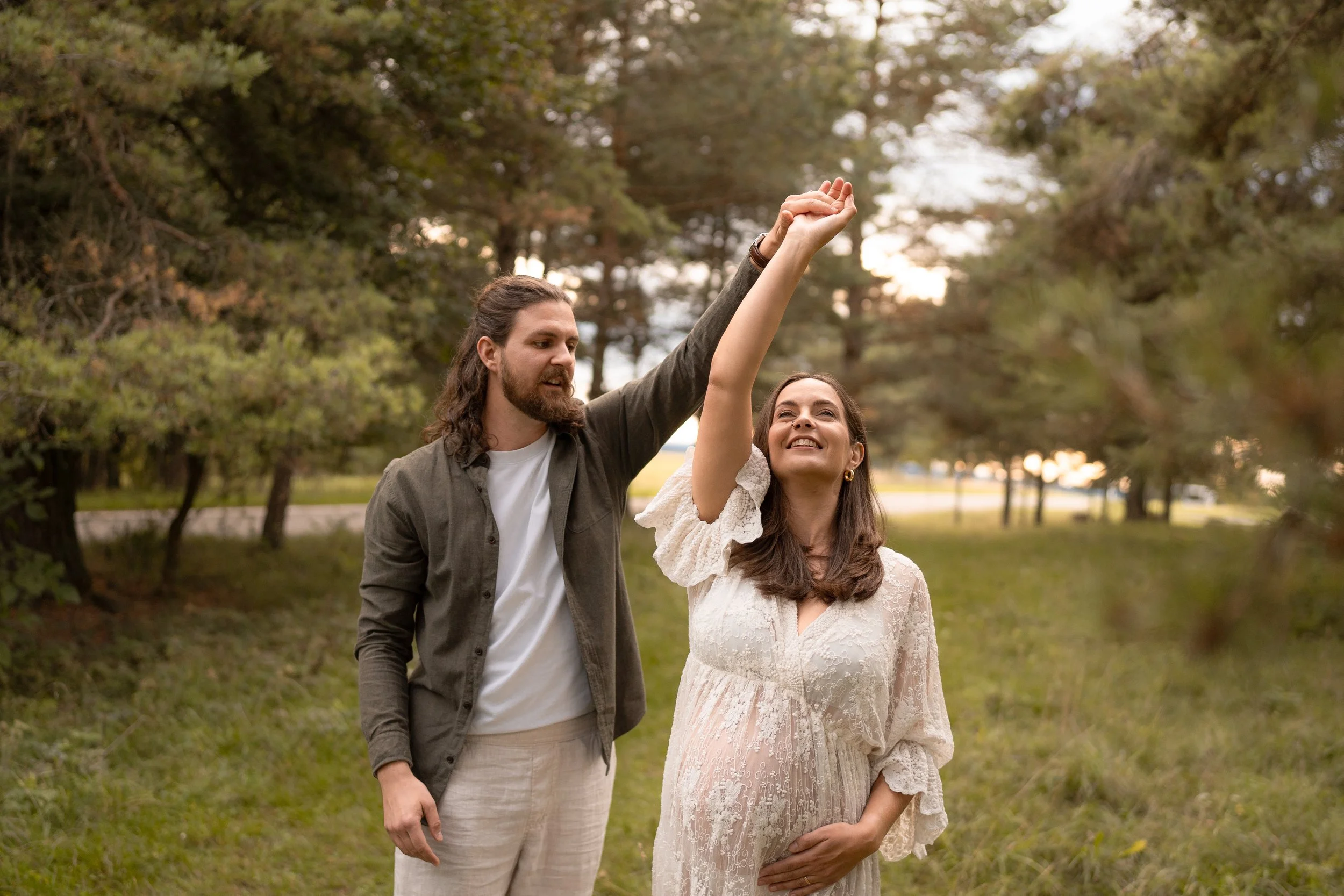 Ein Paar, das draußen im Park sitzt, ein schwangere Frau lächelt, während der Mann sie berührt