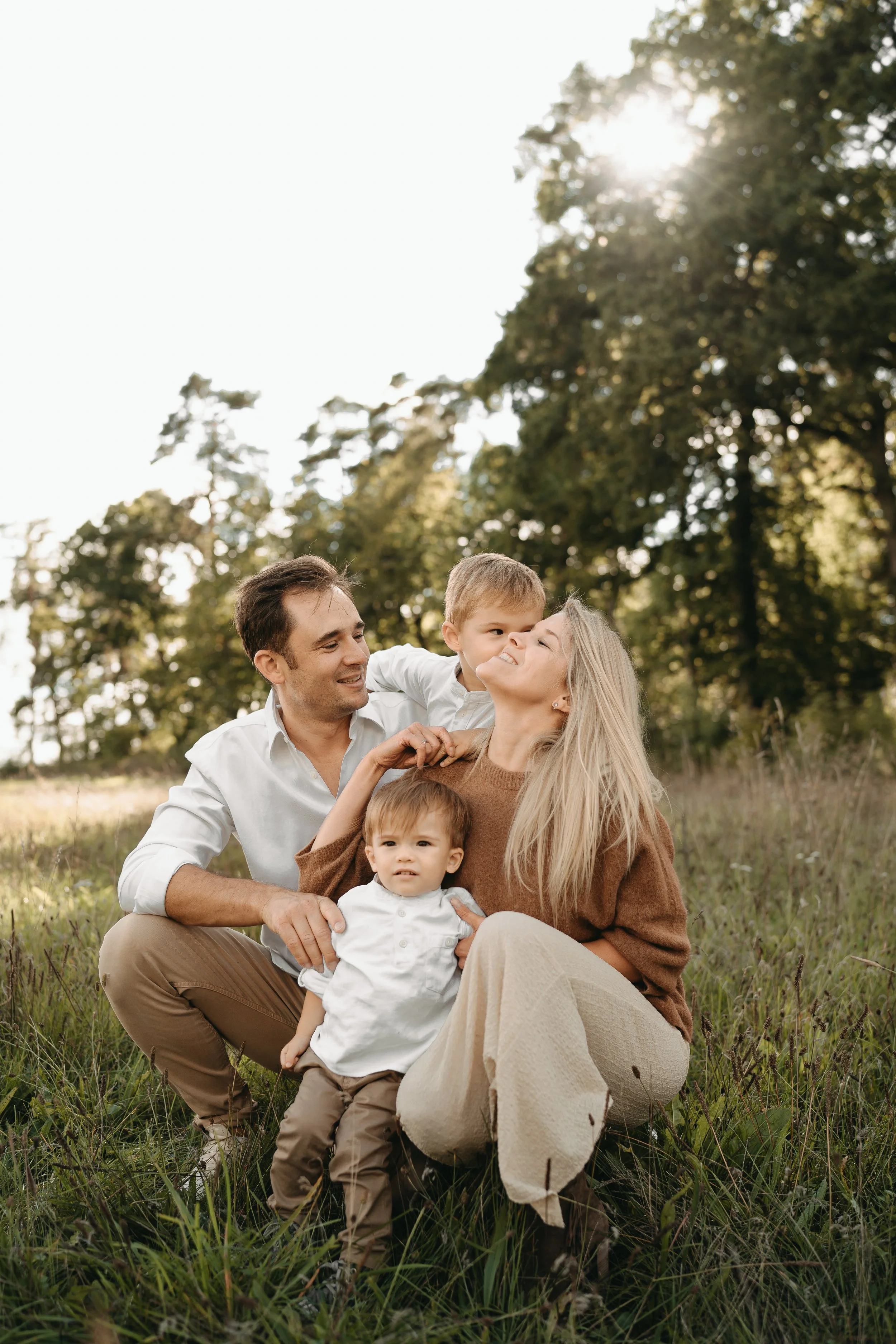 Familie mit zwei kleinen Kindern im Grünen bei Sonnenuntergang.