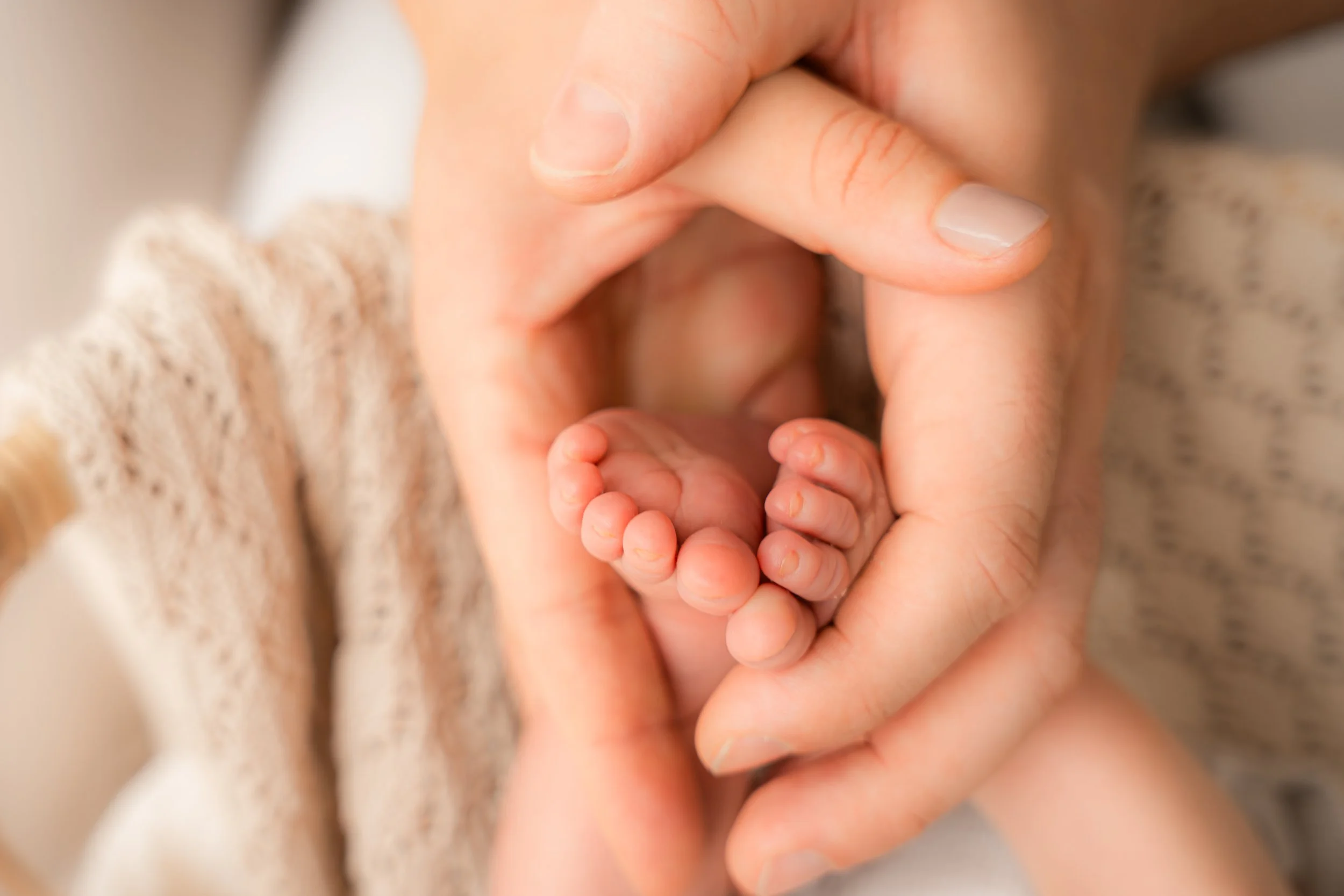 Nahaufnahme einer Hand, die einen winzigen Babyfuß hält.