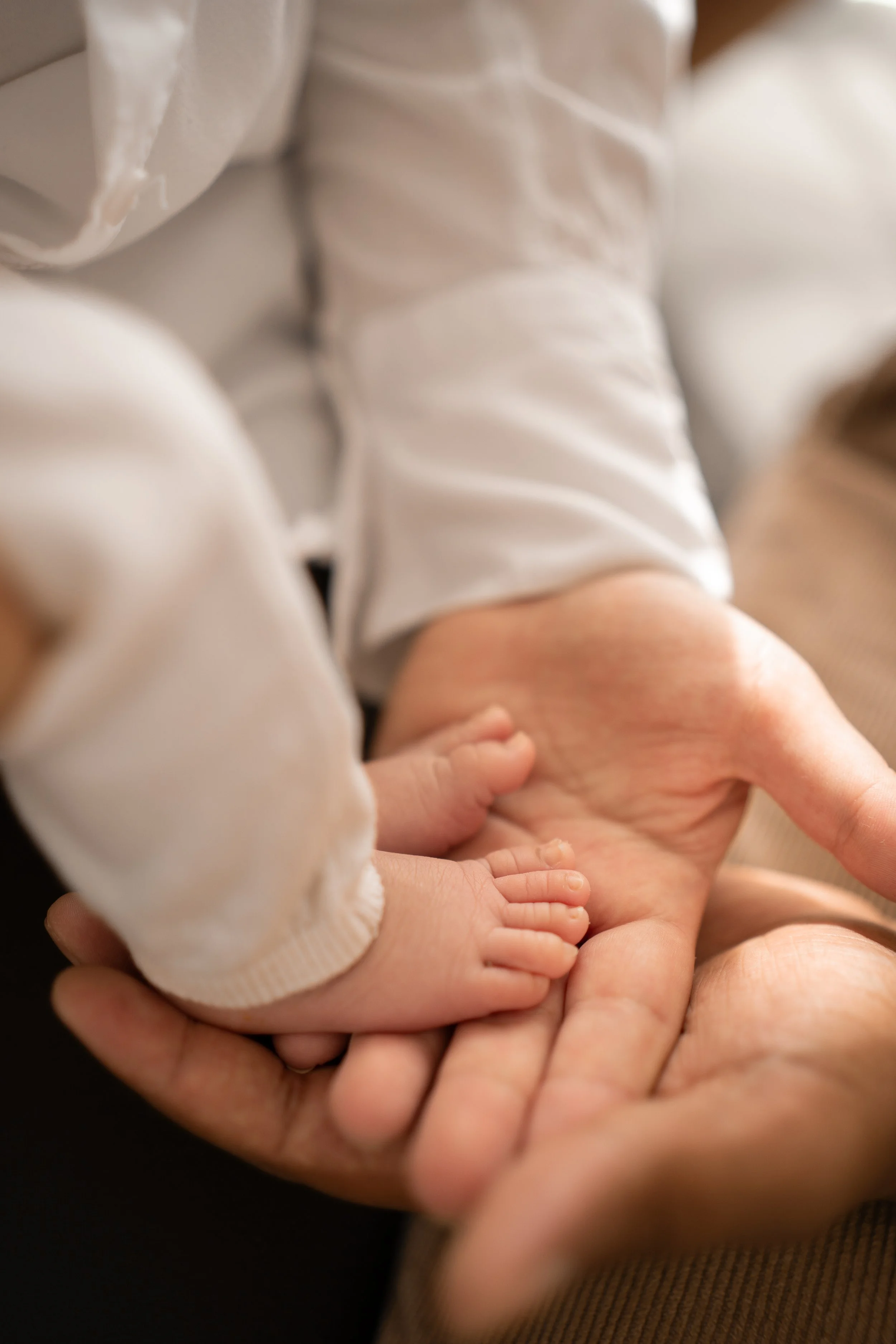 Nahaufnahme einer Hand, in der ein kleiner Kinderfuß liegt, umgeben von einer erwachsenen Hand.