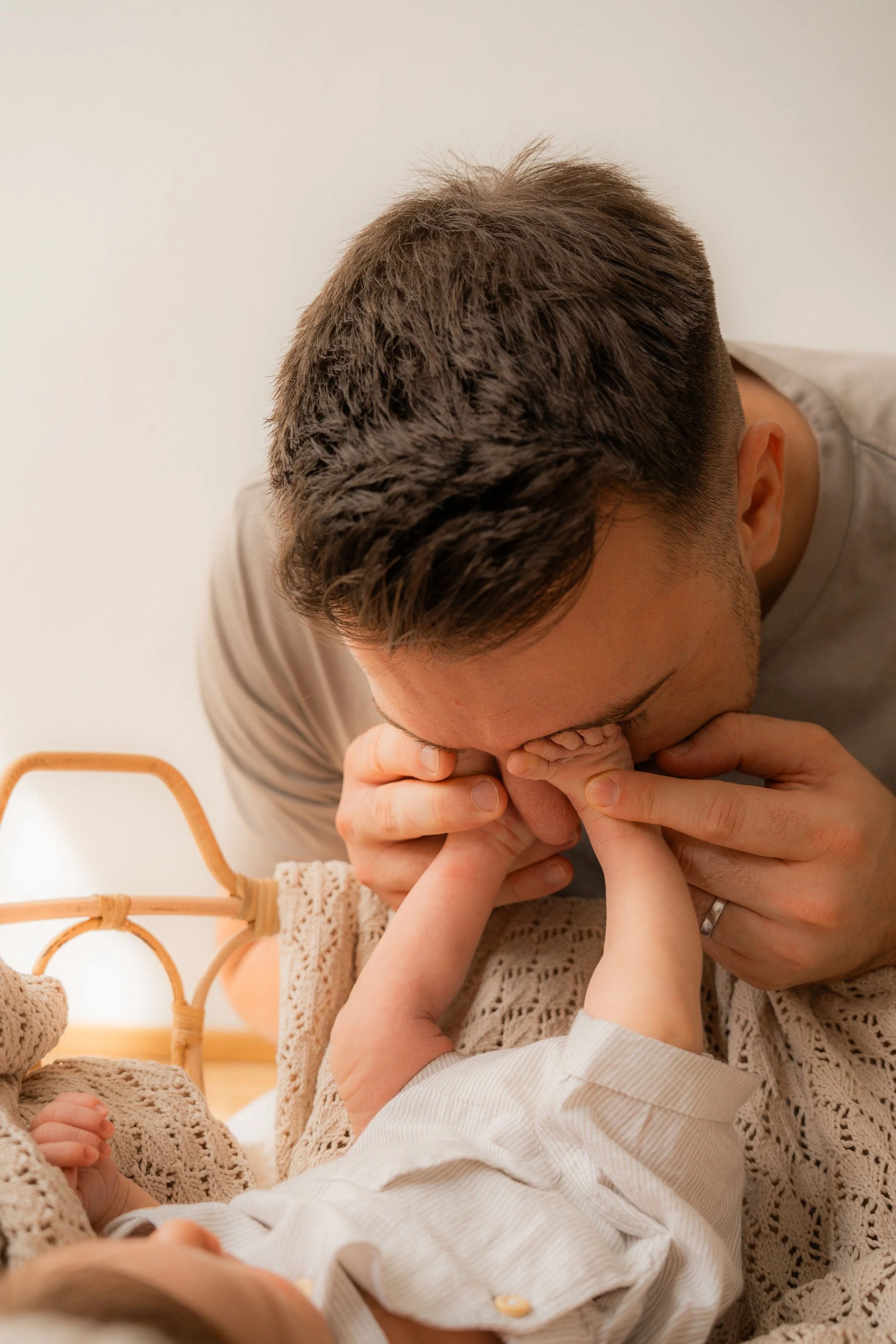 Vater küsst und umarmt neugeborenes Baby, das im Bett liegt.