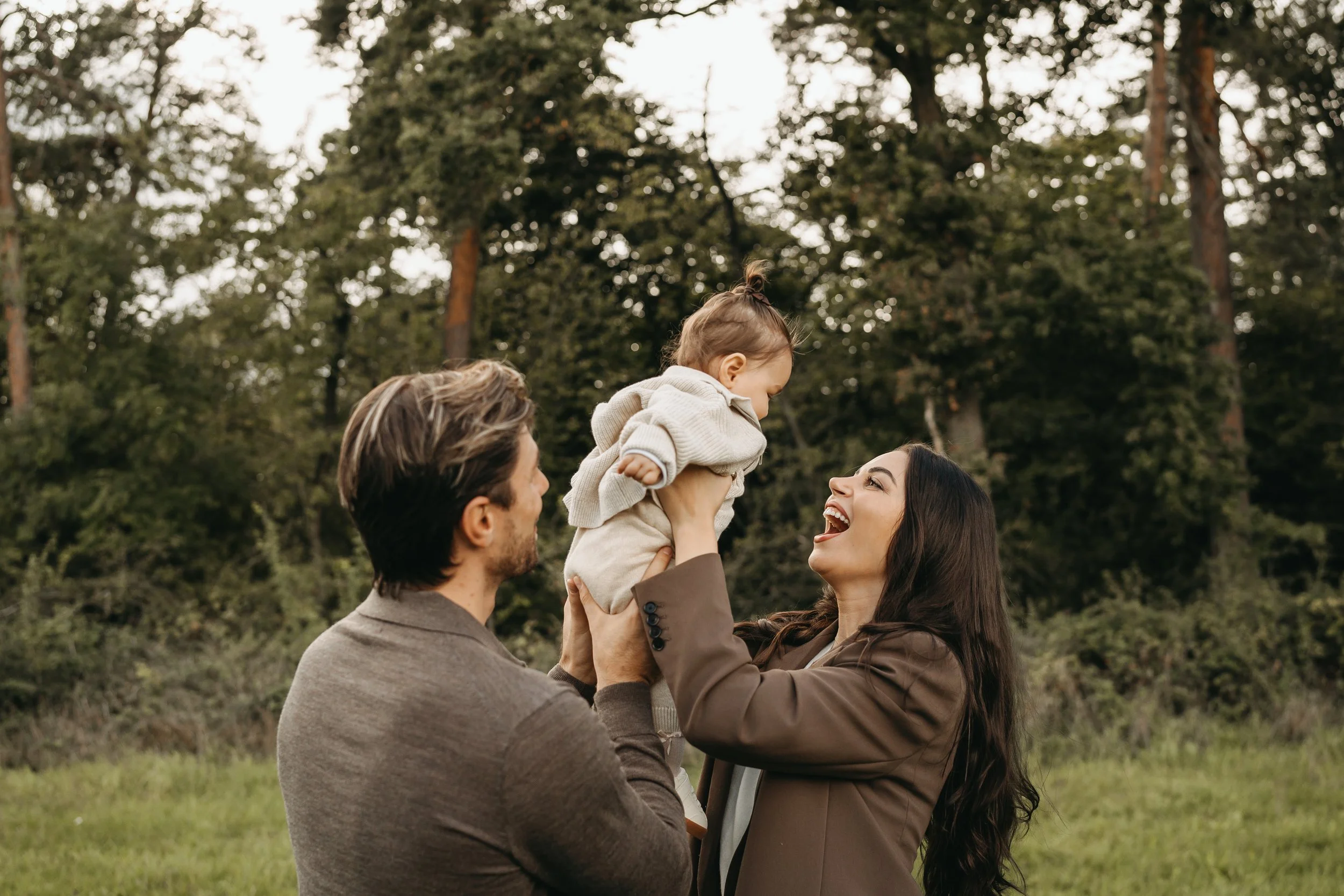 Ein Paar mit einem kleinen Kind in einem Park, alle lachen und genießen den Moment.