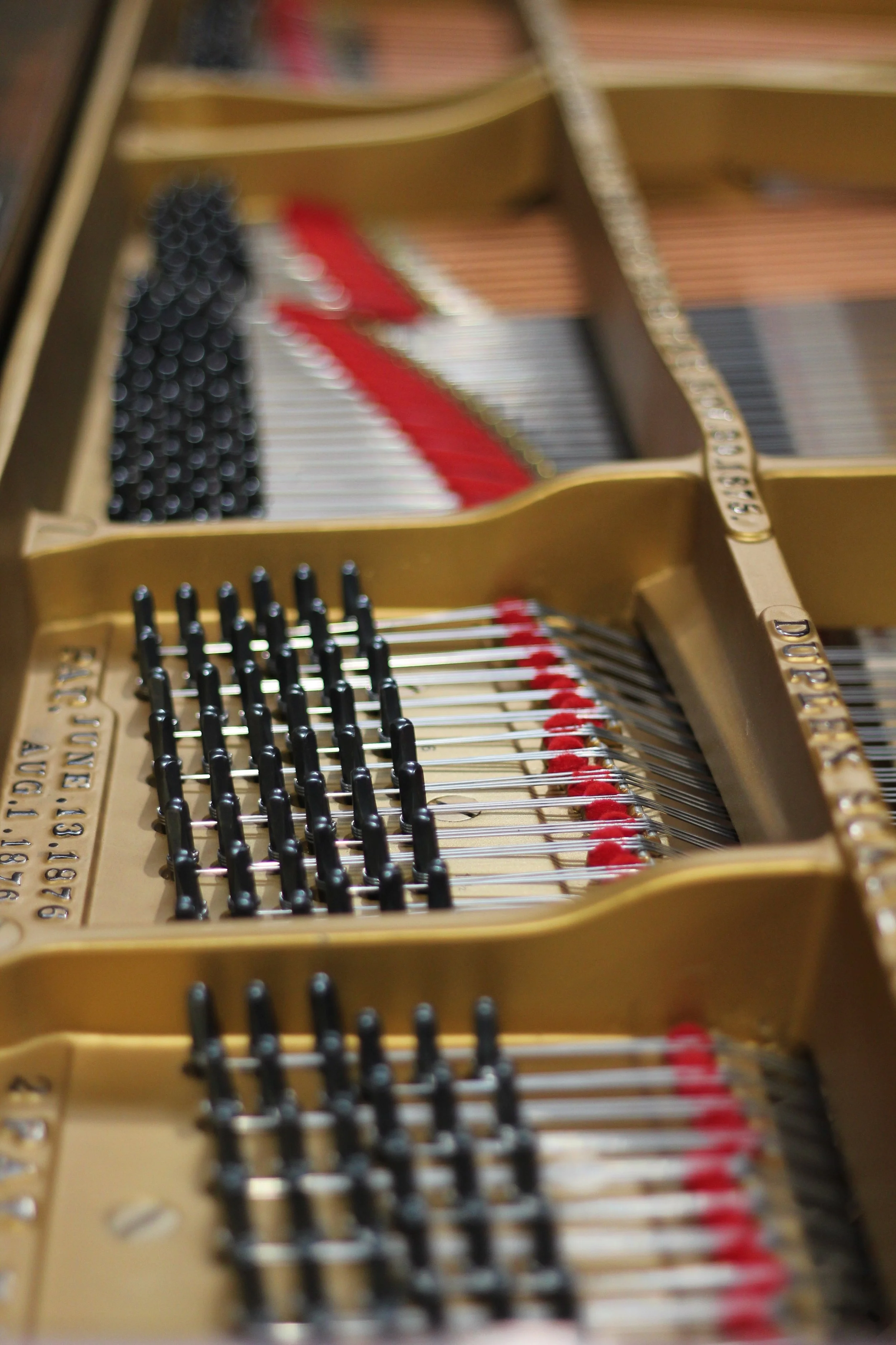 Close-up of the inside of a grand piano showing strings, tuning pins restored