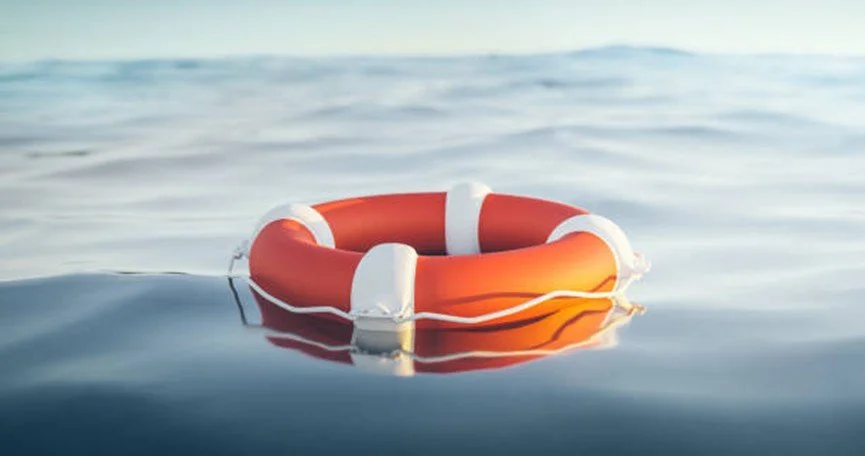 Bright orange lifebuoy floating on still water—symbolizing emotional safety, suicide prevention, and support systems for those in crisis