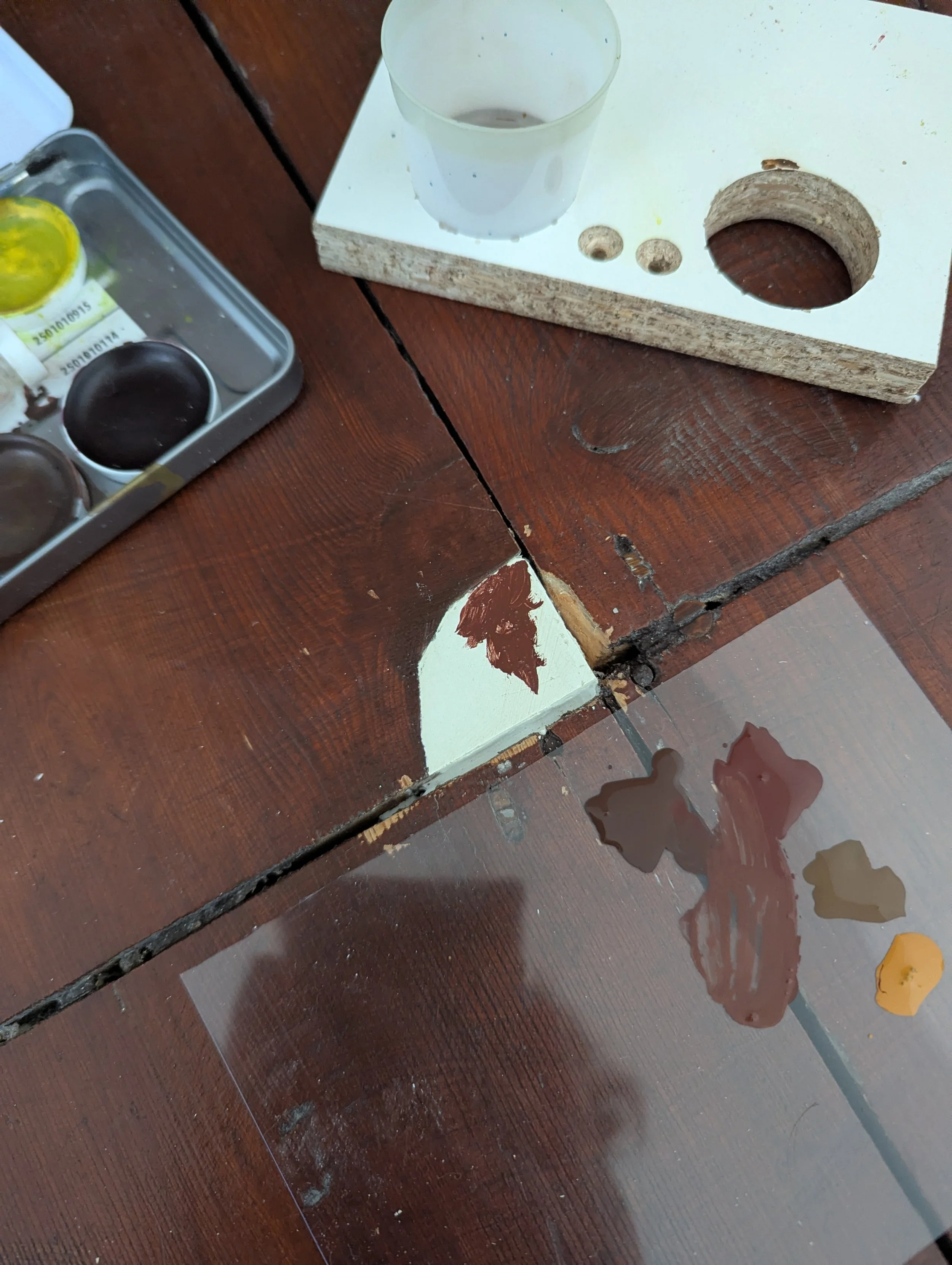 Shows a floorboard being repaired. It had a missing chip, which was repaired and painted