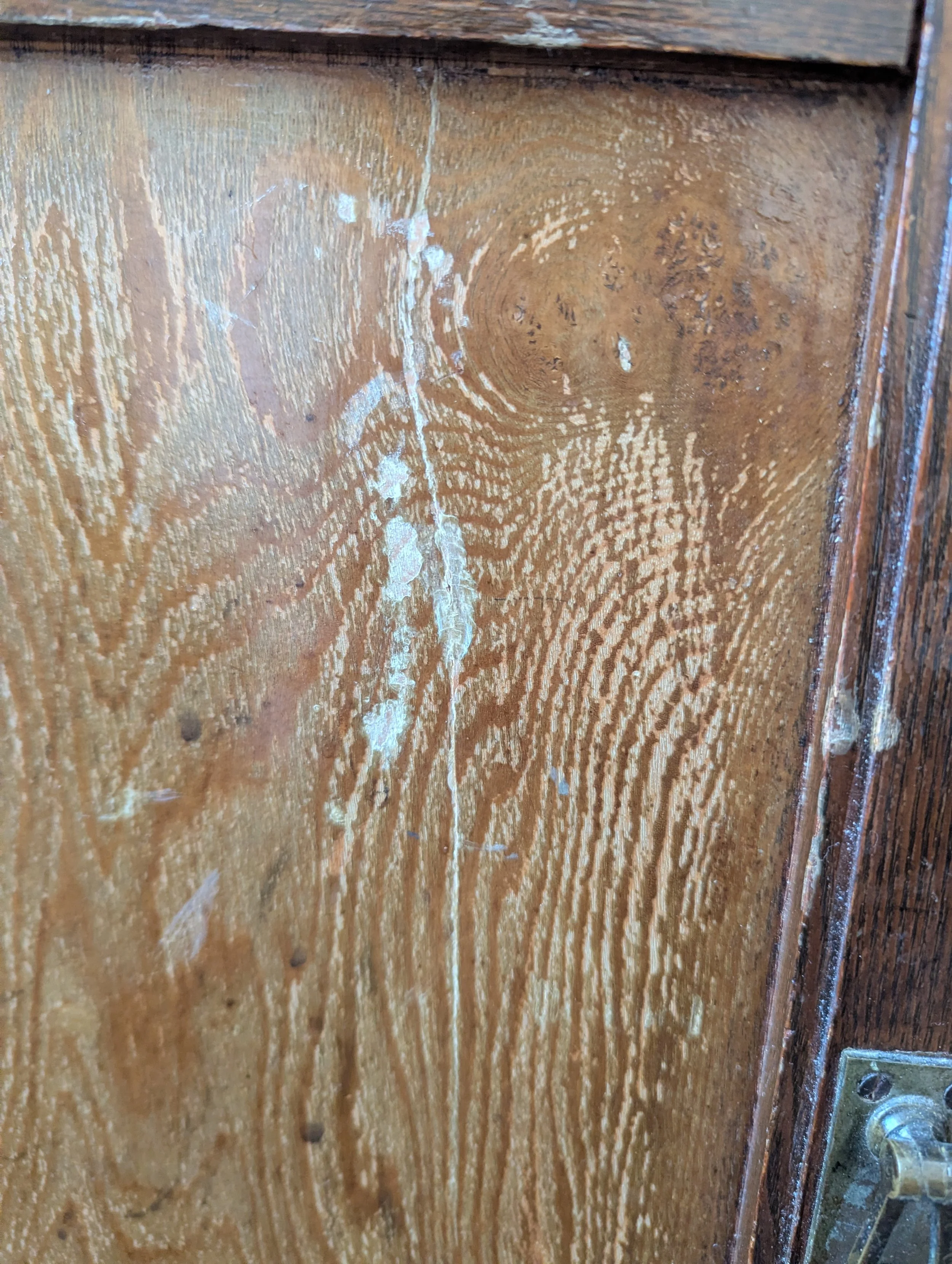 The image shows a deep scratch in the face of an antique cabinet before the cabinet is repaired.
