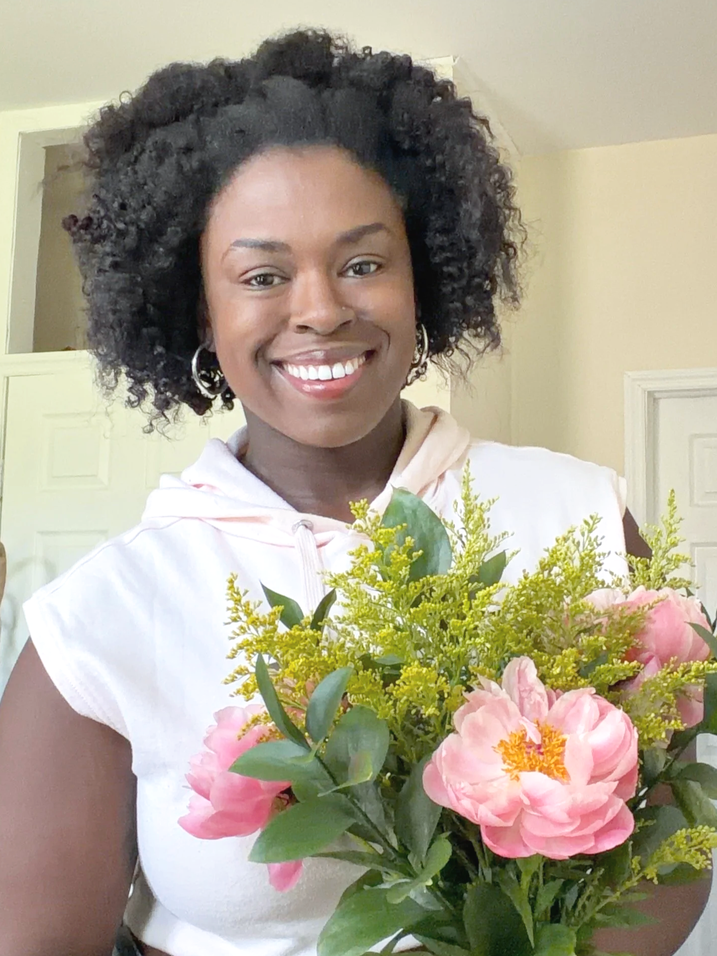 Florist at oncidia floral design smiling while holding a bouquet of flowers.