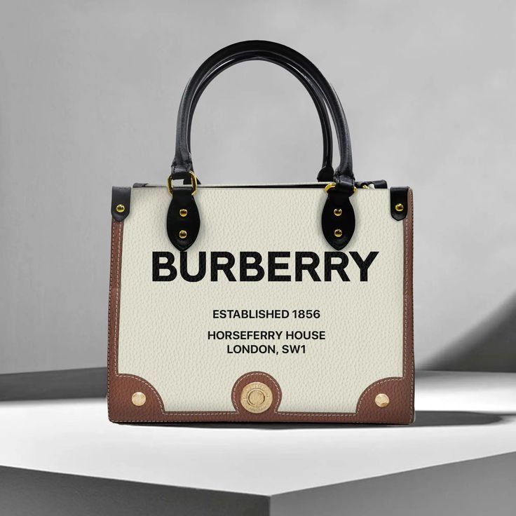 A Burberry handbag with black handles, displaying the brand name and establishment details on a white background with brown and black accents.