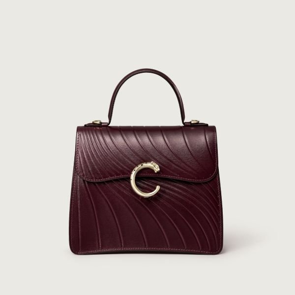 A burgundy leather handbag with a gold clasp and handle design.