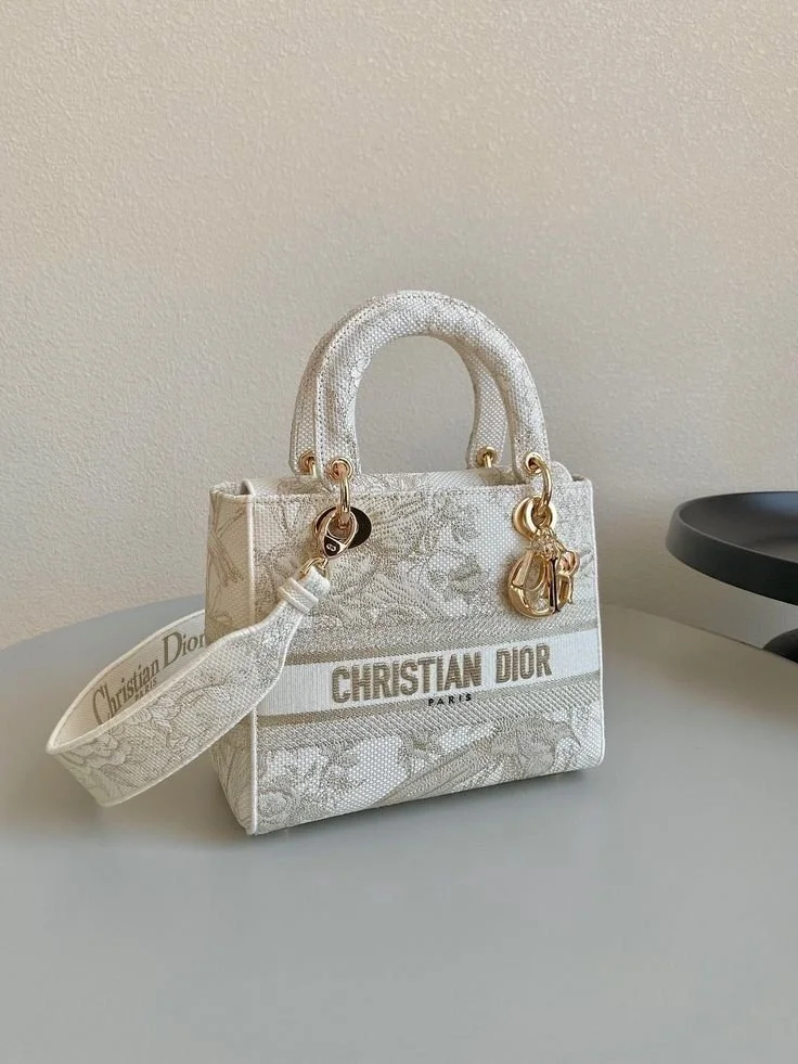 A white Christian Dior handbag with gold hardware and the brand name "Christian Dior" on the front, placed on a flat surface.