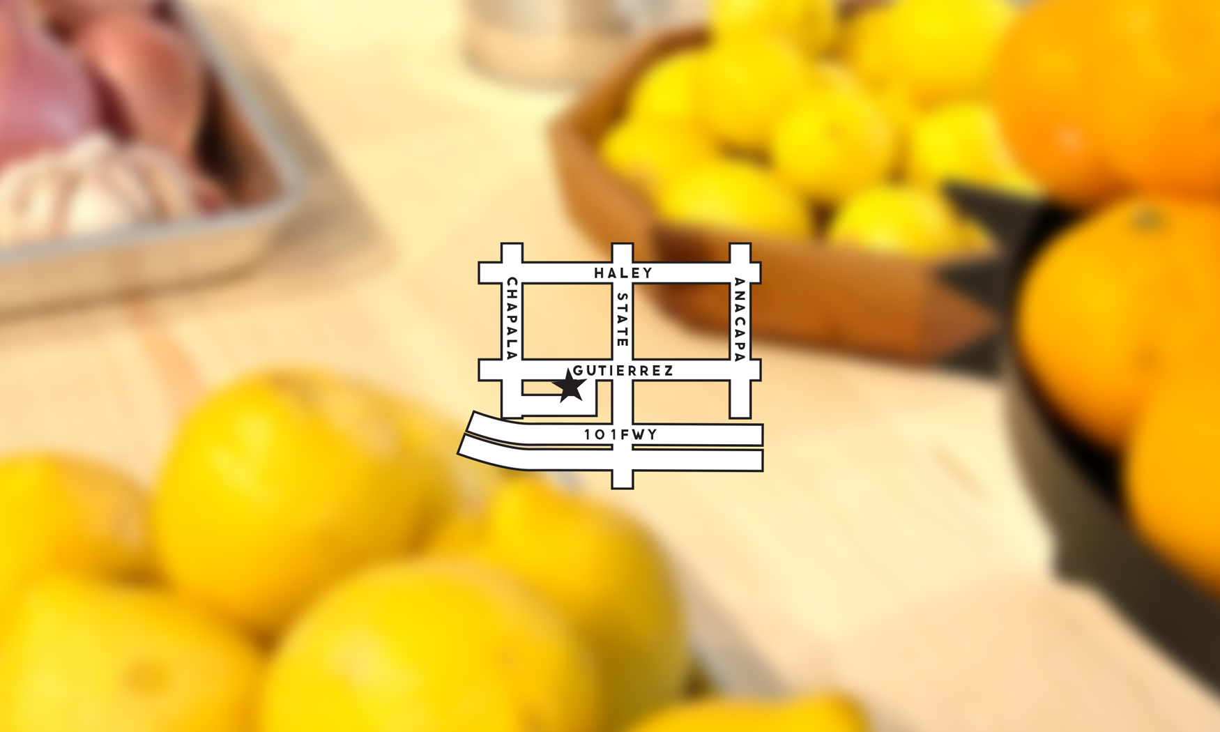 A blurred background showing a bowl of yellow lemons, orange, and a dish of meat, with a small map overlay in the center.