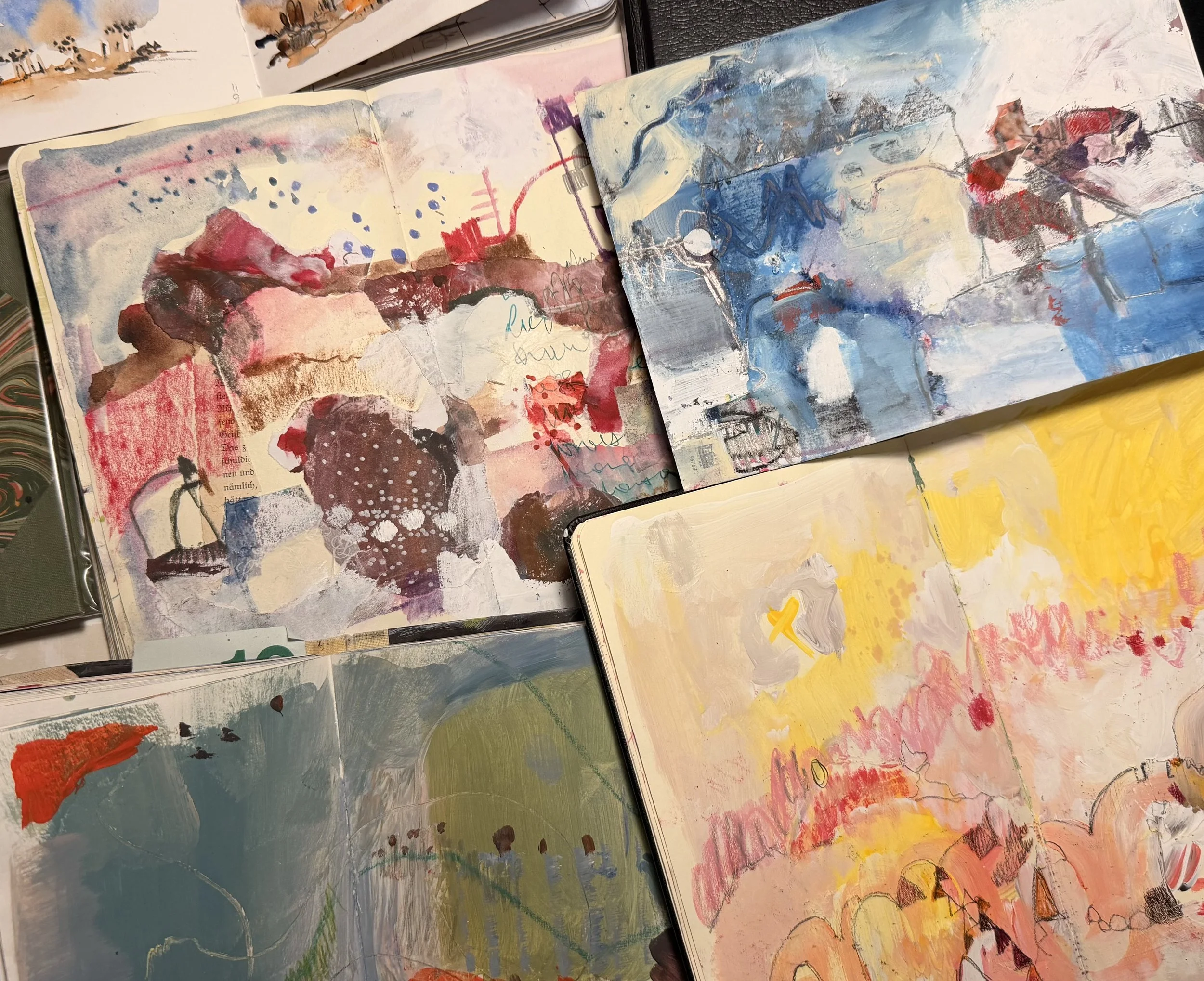 Open sketchbooks with abstract watercolor and mixed media artwork, featuring vibrant colors like pink, blue, yellow, and orange, with scribbles and layered textures.