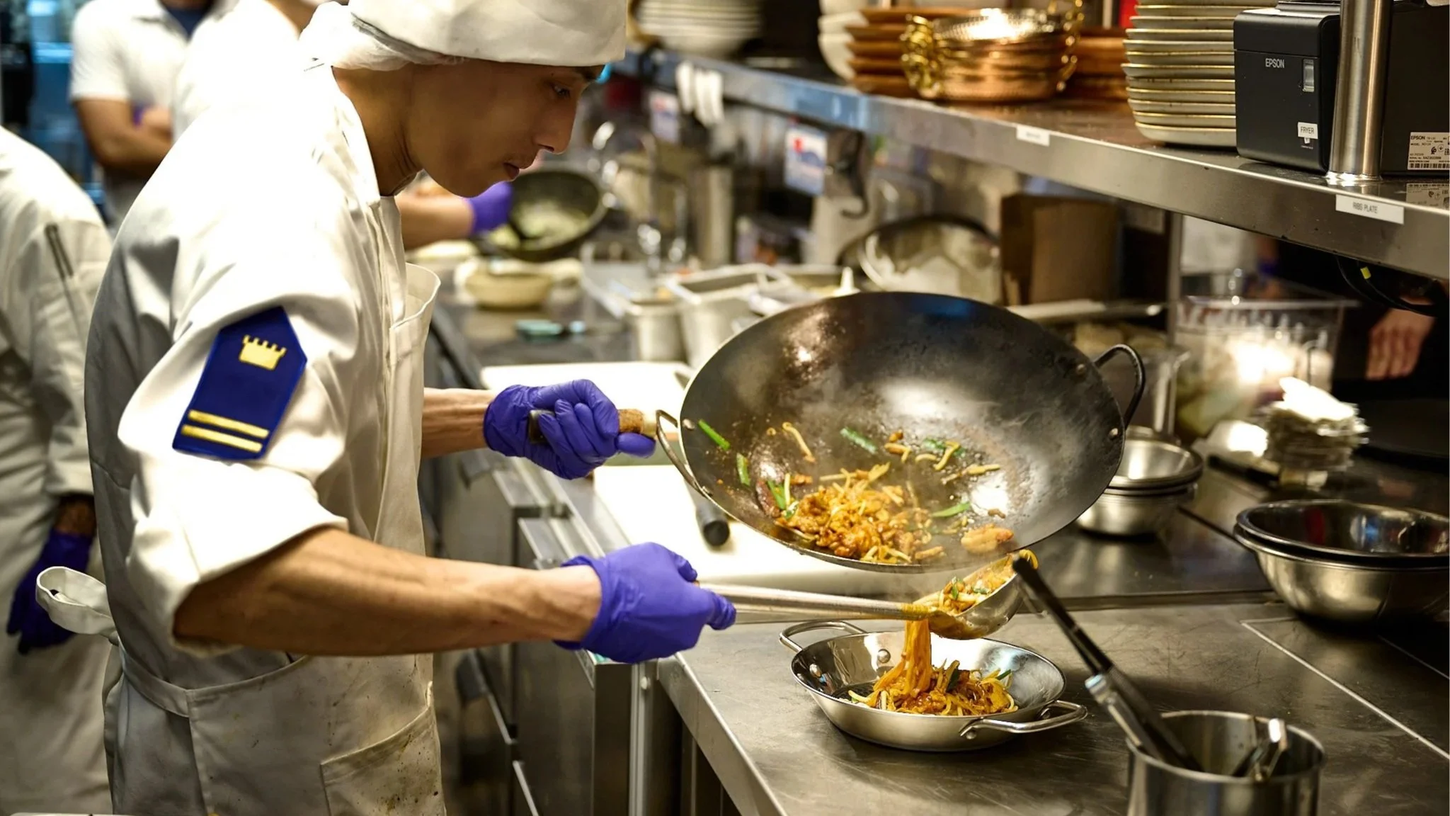Chef stir-frying Thai cuisine in a professional kitchen, showcasing authentic cooking techniques and fresh ingredients in LA Very Thai Westfield Century City..