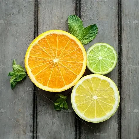 Half orange, lemon, and lime slices with mint leaves on a wooden surface.
