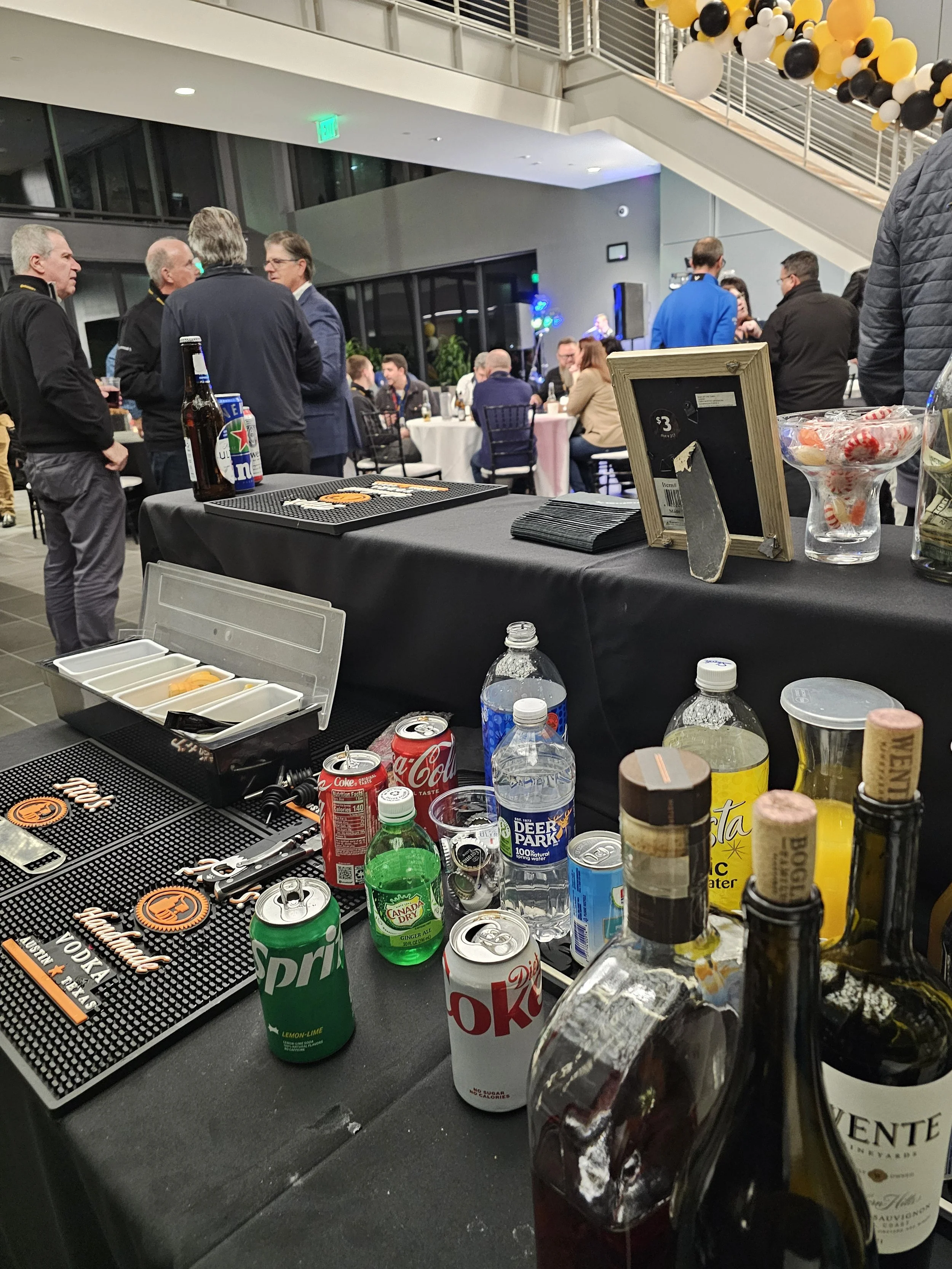 Party scene with drinks on counter, people mingling and talking in the background at an indoor event
