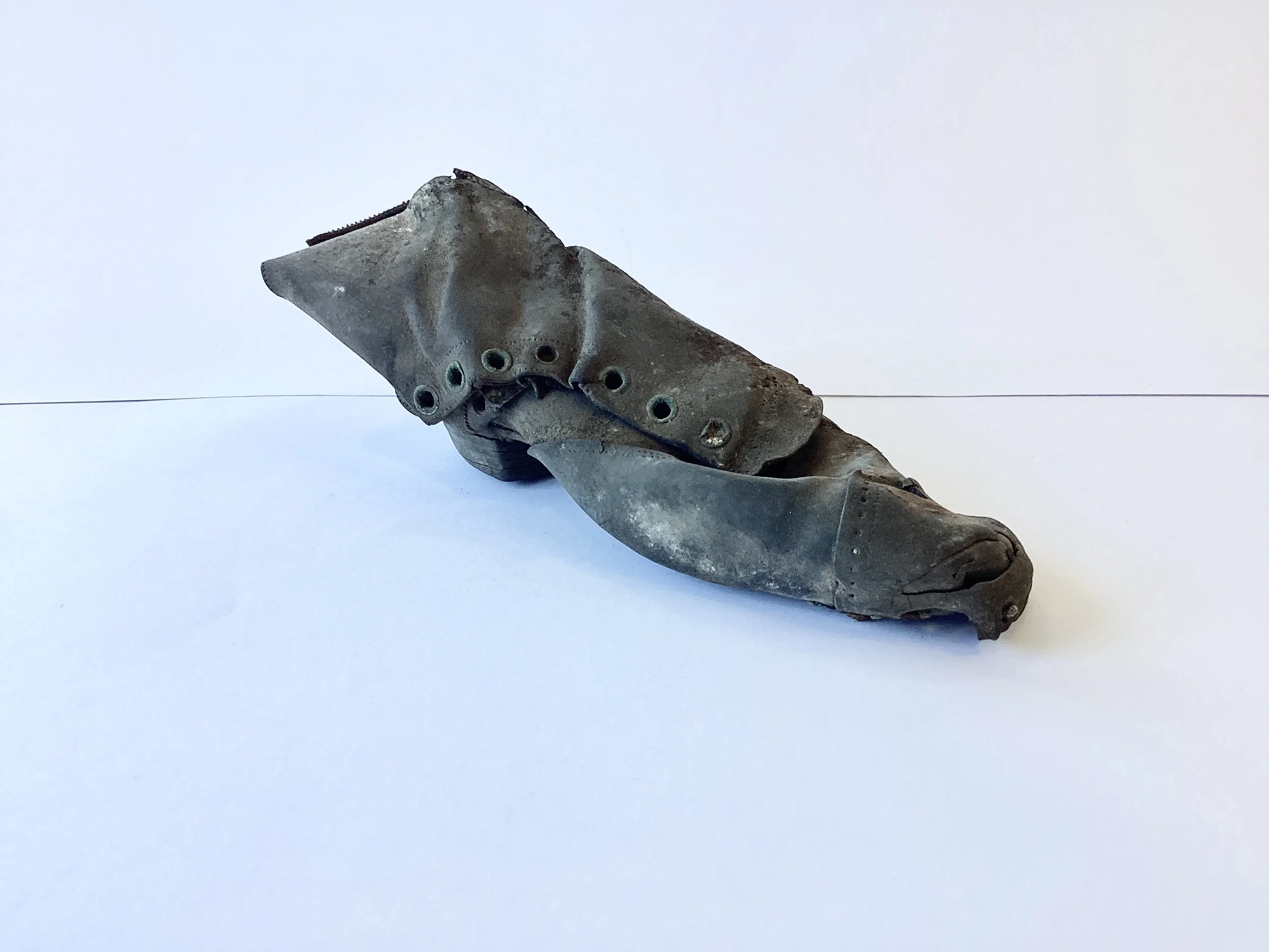 A small, weathered prosthetic foot with a tenon socket, lying on a white surface.