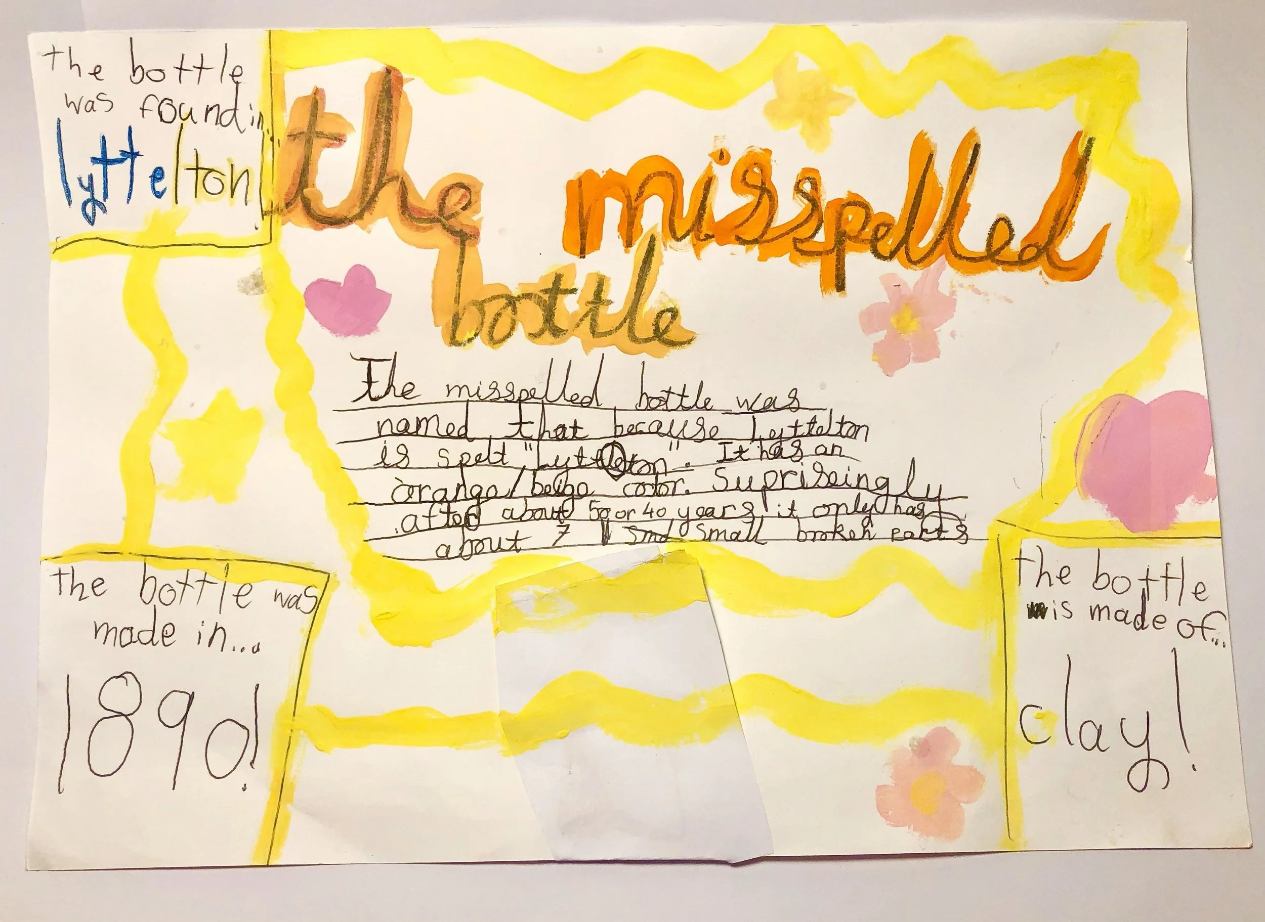 A colorful, hand-drawn poster about a misspelled bottle. The poster has yellow borders, pink flowers, and various parts of text in different colors and handwriting. The main title says "the misspelled bottle" with "the" written in orange and "misspelled" in orange with a black outline. There are smaller text boxes stating "the bottle was found in Littleton," "the bottle was made in 1890," and "the bottle is made of clay." The central text explains that the bottle's name is misspelled because "Littleton" is spelled "lettton," has an orange/brown color, and is about 40 or 50 years old, with small cracks.