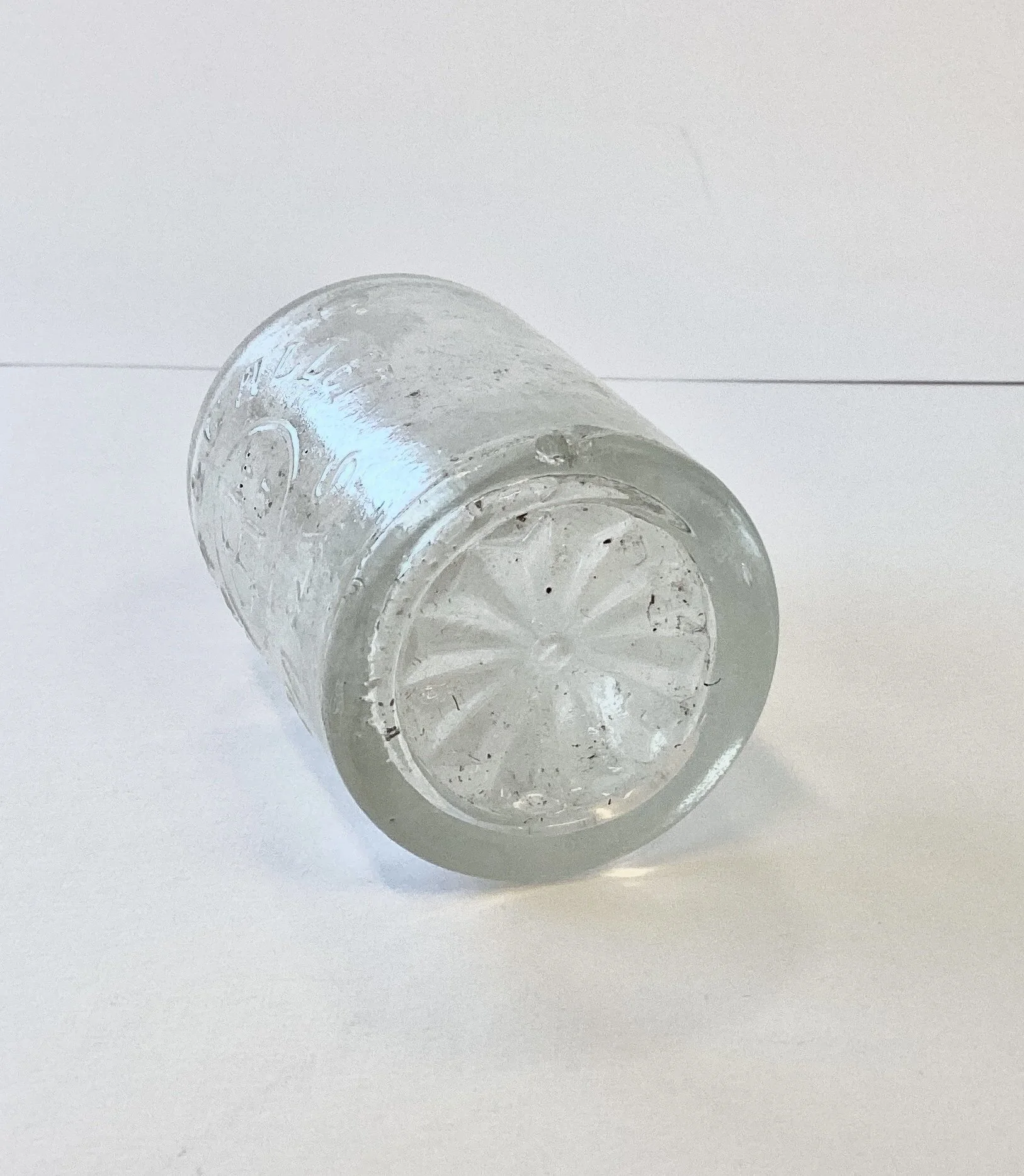 A clear glass bottle lying on its side on a white surface.