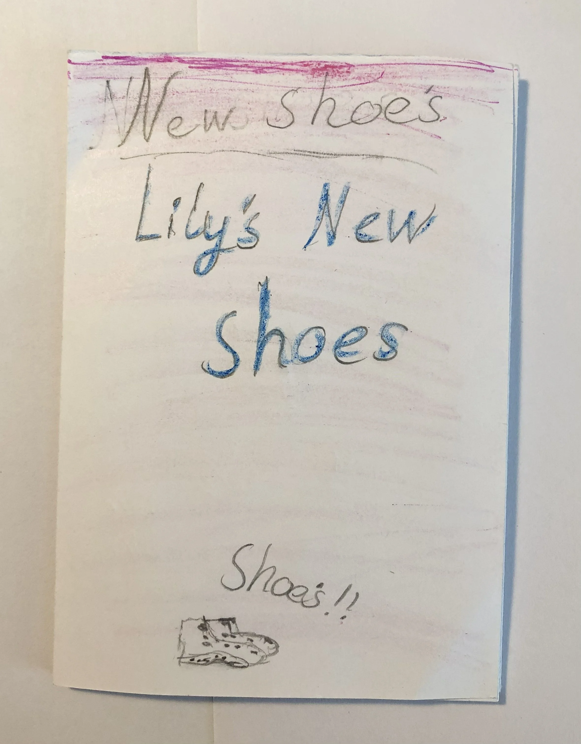 A handwritten sign on a piece of paper advertising new shoes, with the words 'New Shoes', 'Lily's New Shoes' written in colorful marker, and a small drawing of a boot at the bottom.