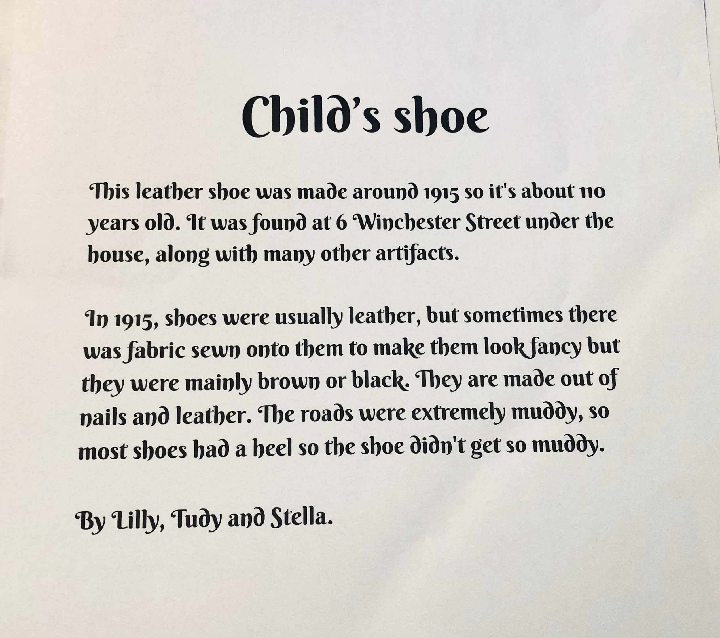 An informational sign about a child's shoe, describing its history, material, and conditions from around 1915, found at 6 Winchester Street.