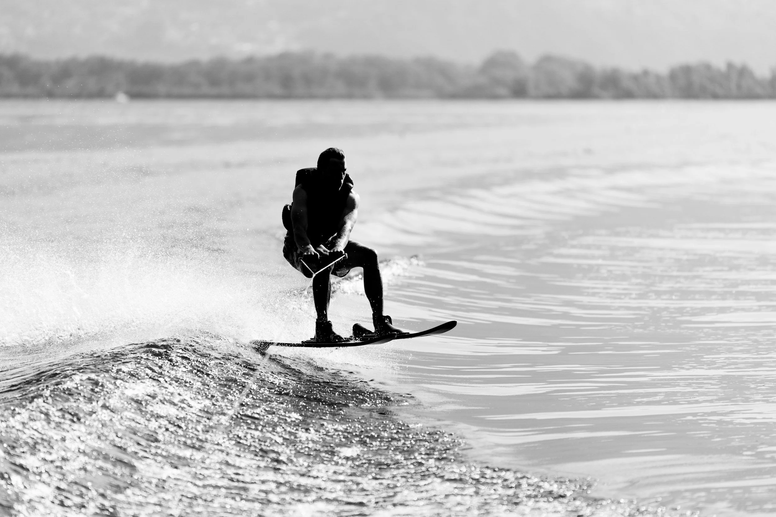 A person waterskiing on a lake with trees in the background, black and white photo.