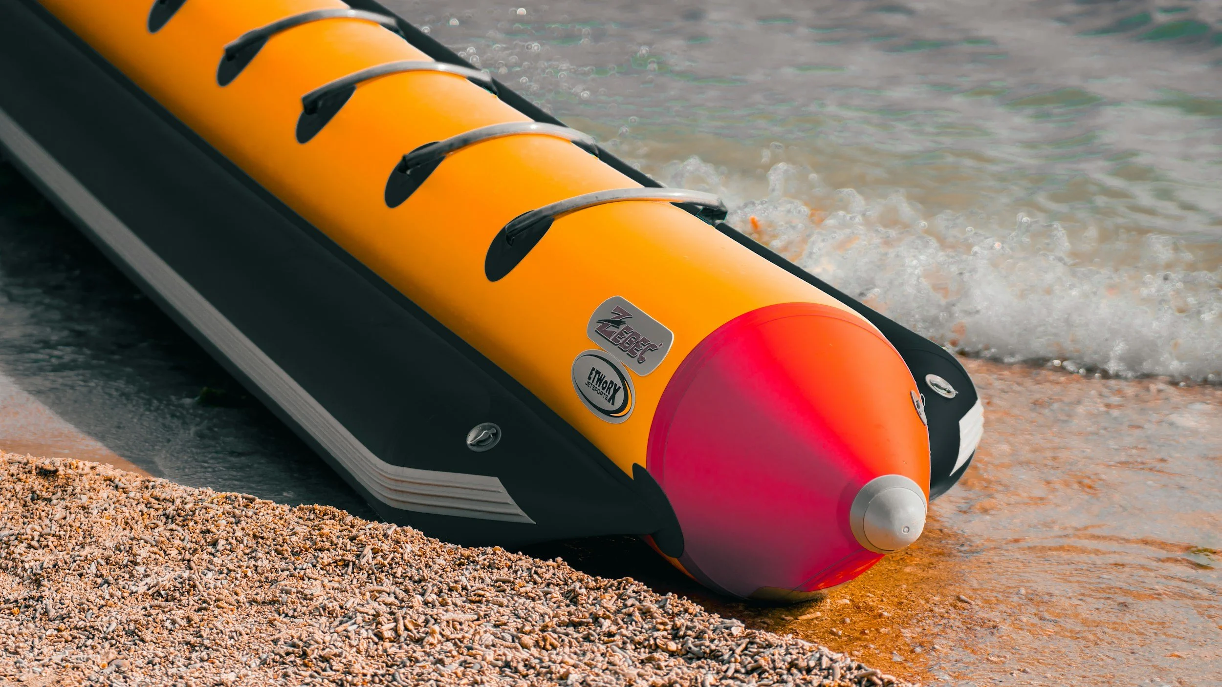Inflatable yellow and pink boat on the shore at the water's edge