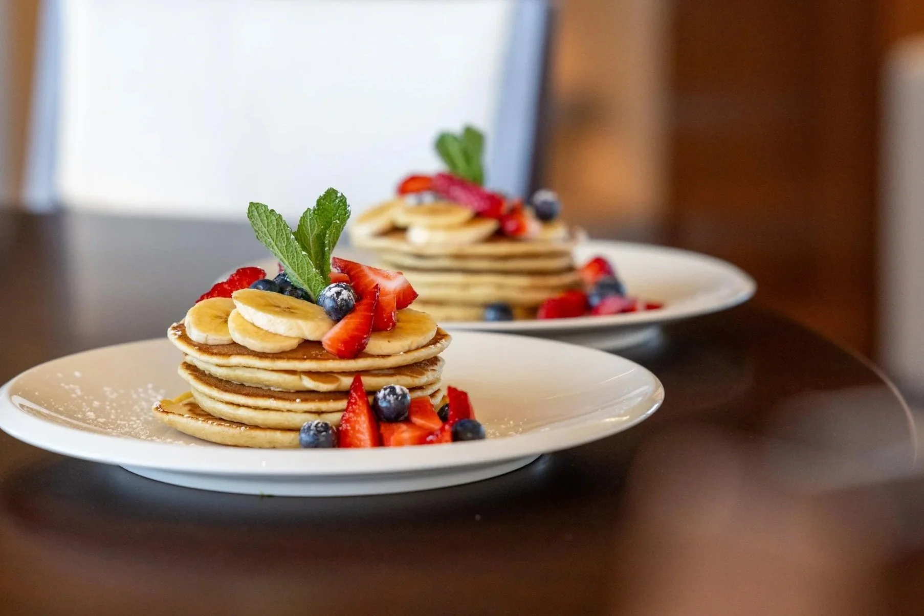 Plated pancakes with fruit and mint leaf garnishing