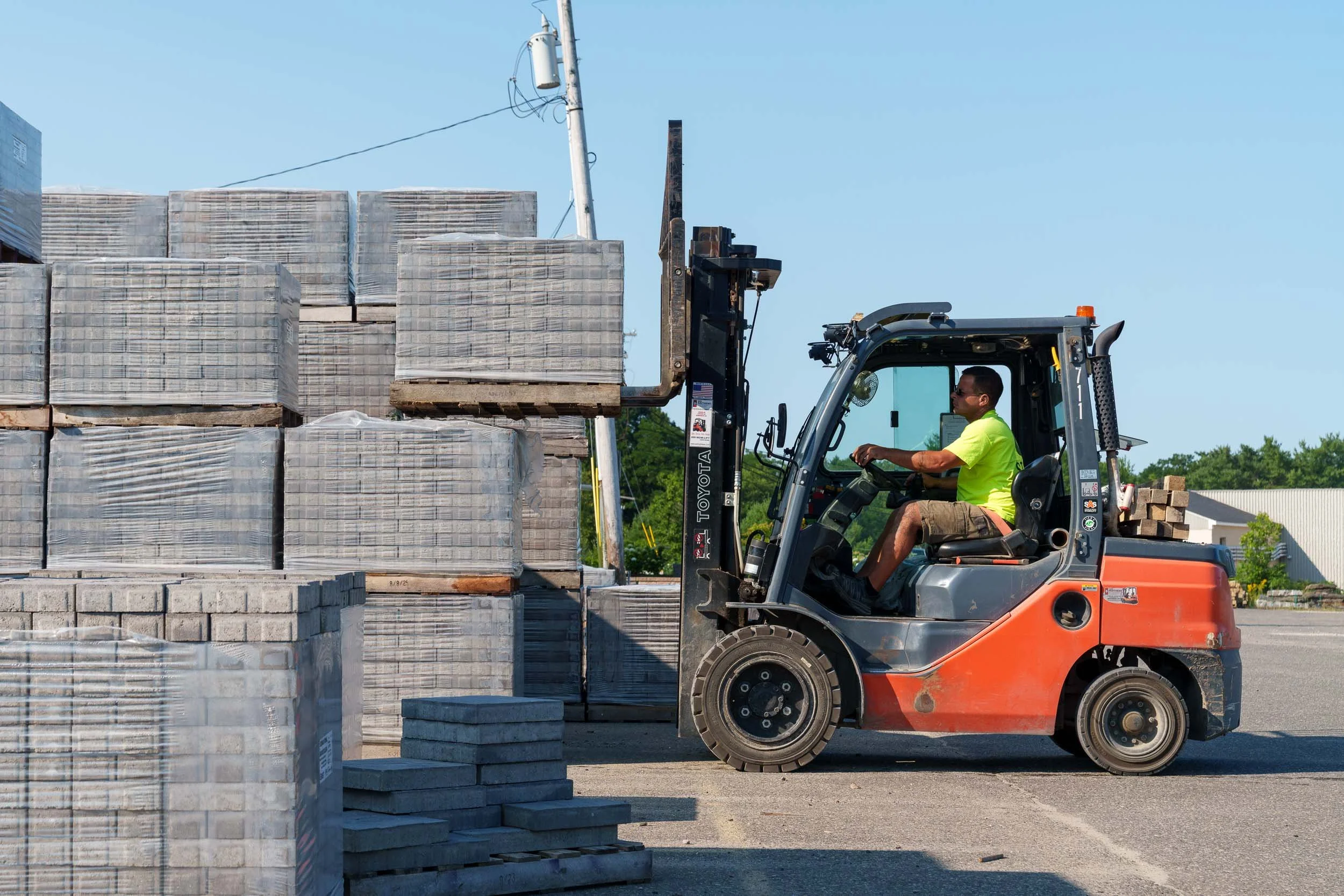 Genest Concrete Biddeford, Maine showroom inventory yard workers using a forklift to load hardscaping materials during a commercial photo shoot.