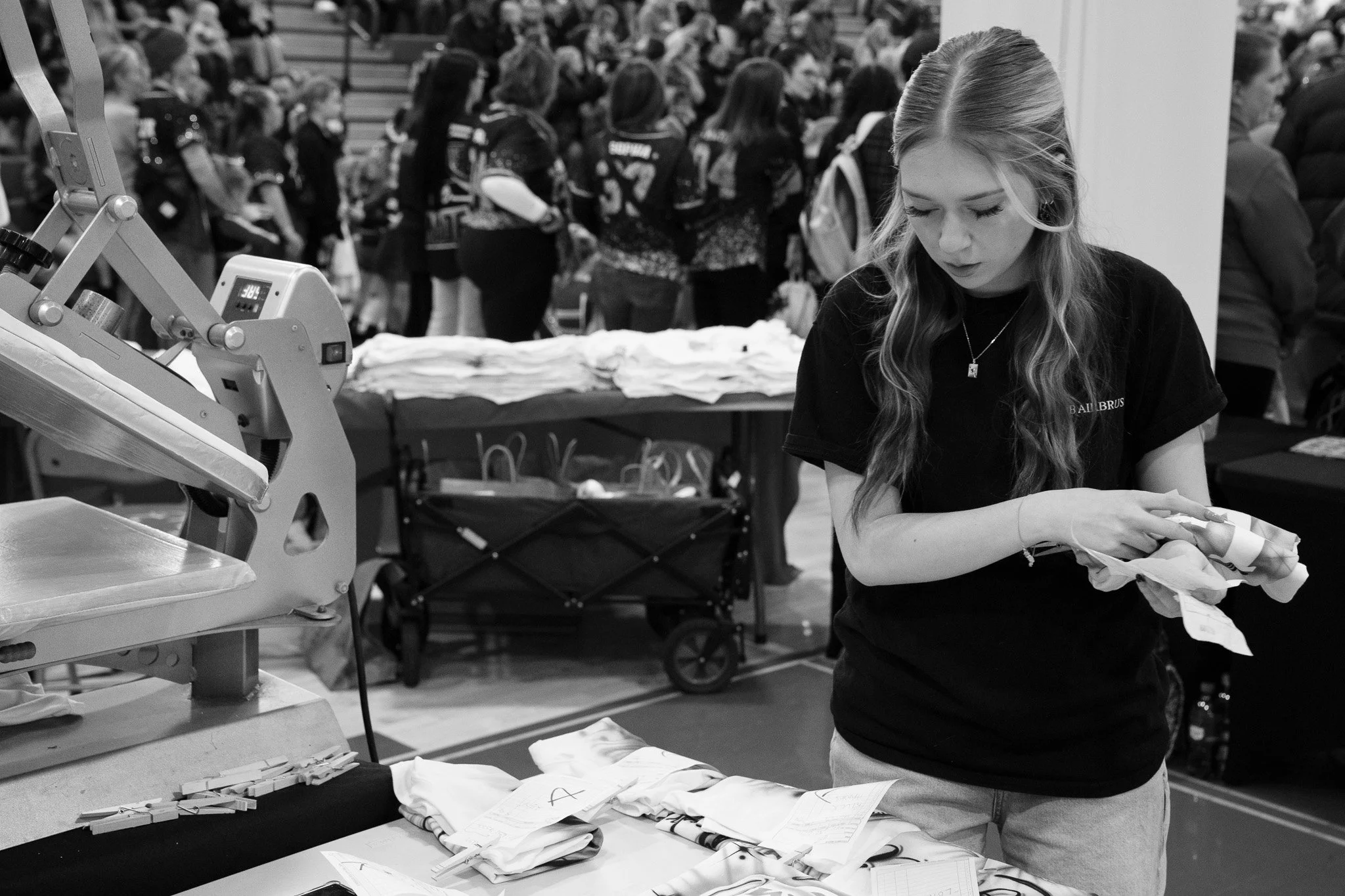 A young woman working at a Custom Airbrush booth during a cheering competition.
