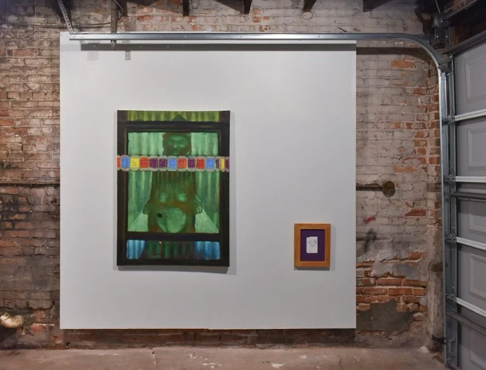 Artwork displayed on a white wall inside an industrial space with exposed brick and a garage door. The main painting depicts a figure behind a window with a green curtain and a colorful banner across the window. A smaller framed piece is hung to the right of the main painting.