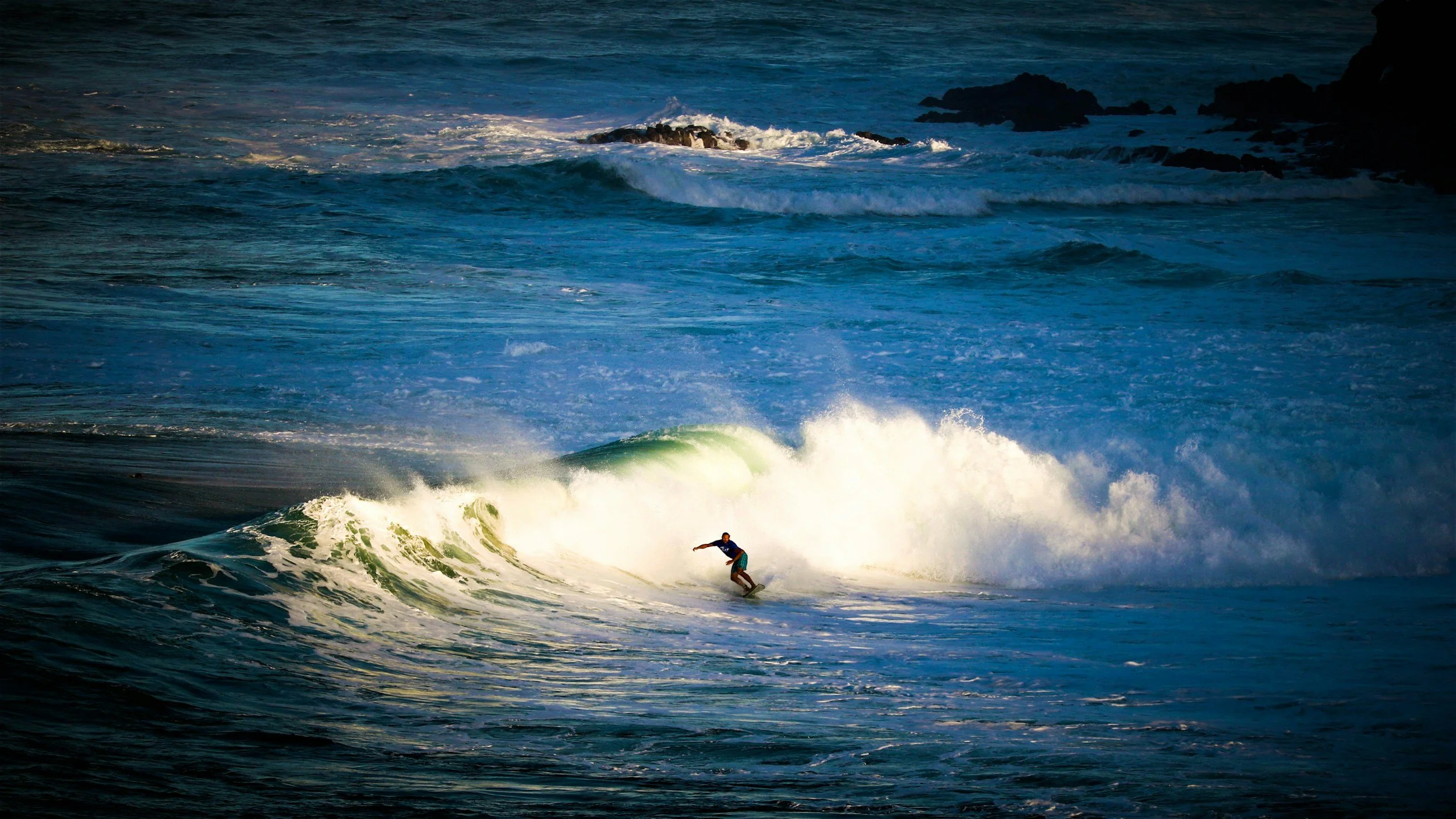 A person surfing on a wave in the ocean during daylight.