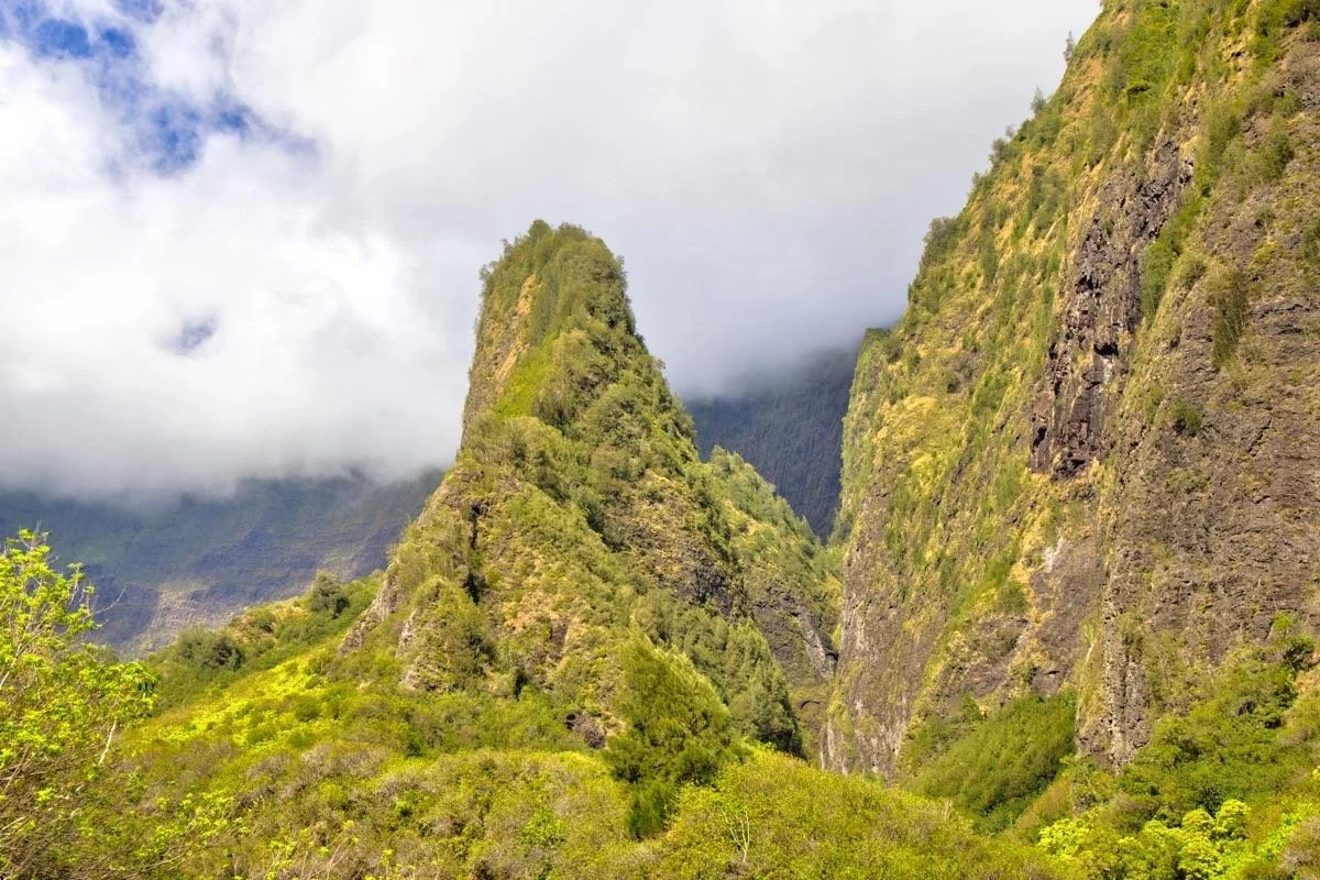 Green mountain peaks with lush vegetation and clouds in the sky.