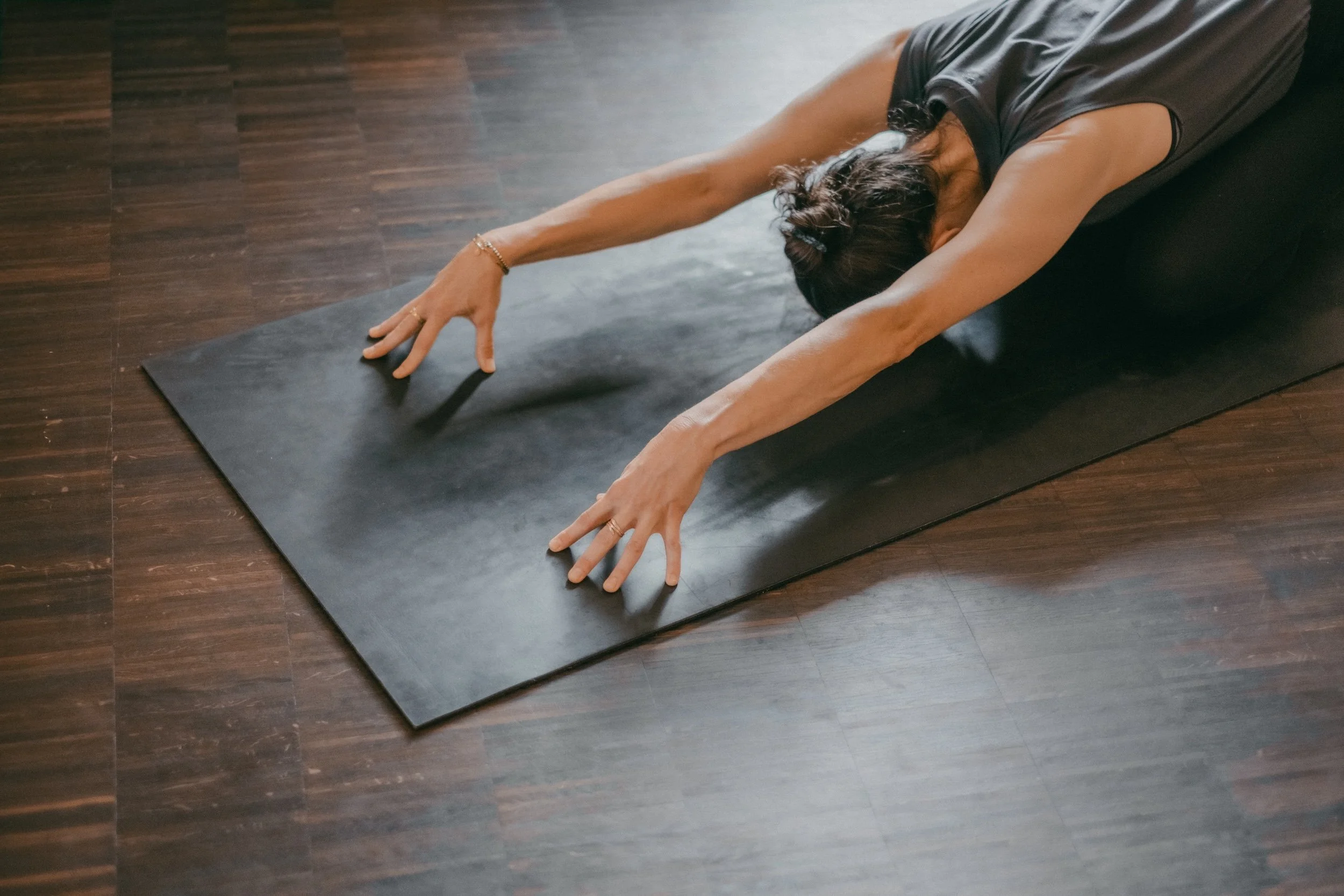 Eine Person, die Yoga macht Haltung des Kindes, Childs Pose, schwarze Yogamatte