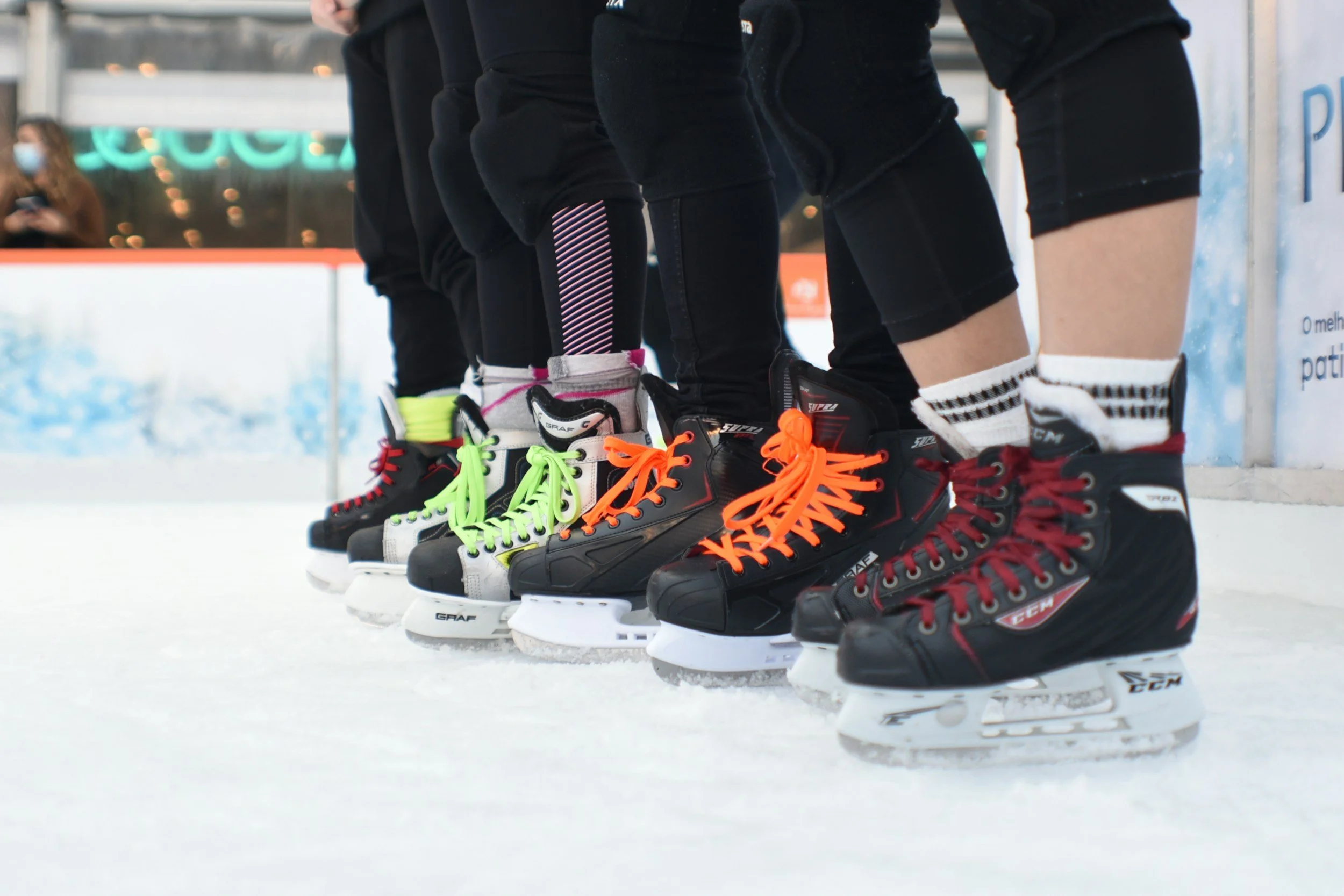 Line of ice hockey players standing on ice rink wearing skates with colorful laces.