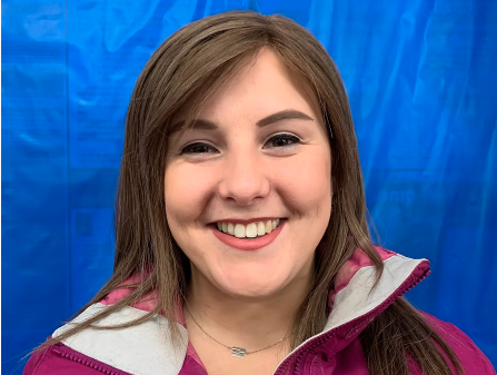 Close-up of a young woman smiling against a blue background.