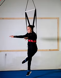 Person using a harness for suspension training in a gym