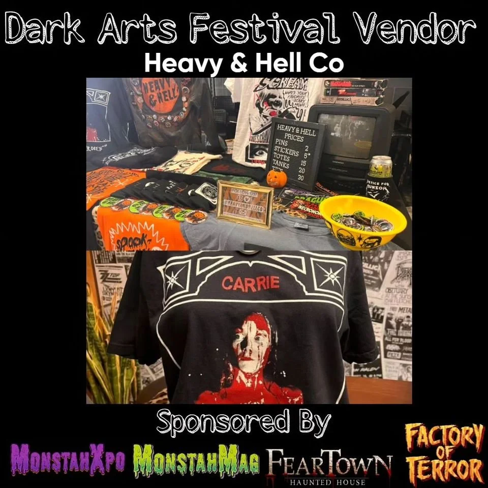 A poster for Dark Arts Festival Vendor Heavy & Hell Co features merchandise on display, including patches, stickers, and tanks. A framed flyer is also visible on the table. The background contains more merchandise and a blackboard listing prices for pins, stickers, and tanks. A shirt with an image of Carrie, a horror character, is prominently displayed in the foreground.