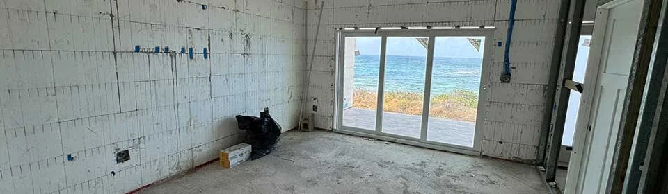 Interior of a house under construction with a large window overlooking the ocean.