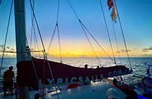 A sunset cruise with Lyric Sail, a large sailboat on the water during sunset with a crew onboard.
