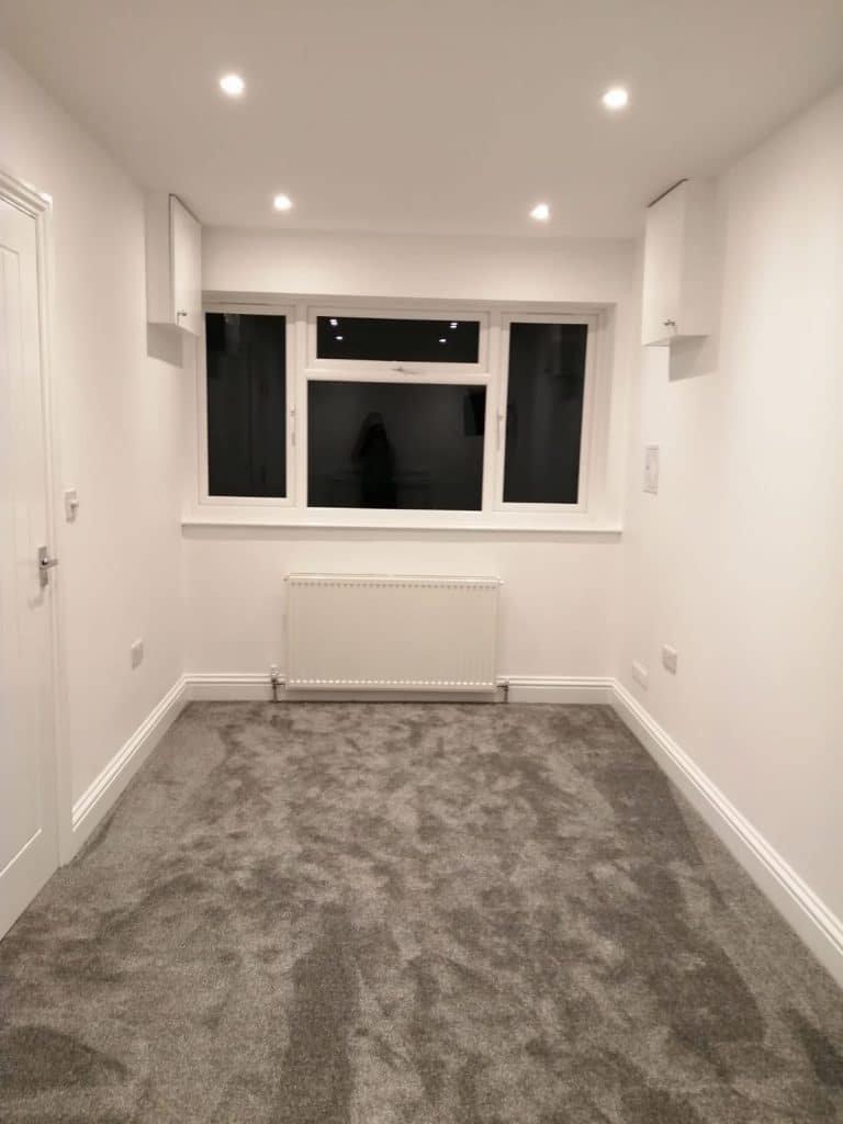 Empty room with gray carpet, white walls, a window, and a radiator underneath the window.