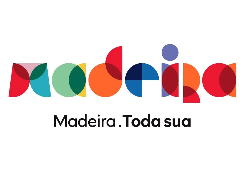 Logo colorido com desenhos de formas geométricas que formam a palavra "madeira" e o slogan "Madeira. Toda sua" em destaque.