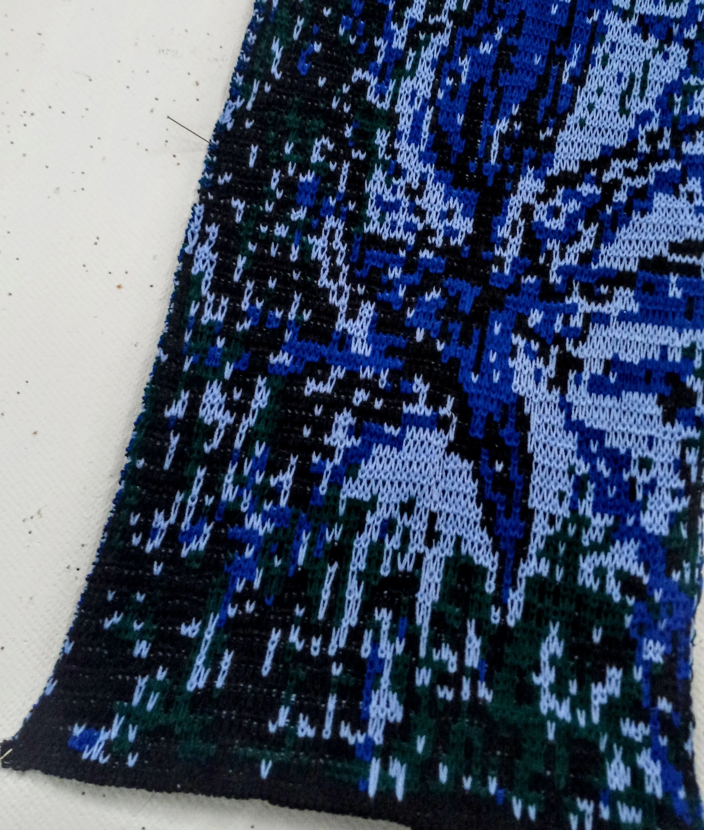 Détail d'un tricot jacquard. La pièce Incise de la série de tricot peinture. Un oiseau bleu éclaté dans un univers bleu, vert et brun.