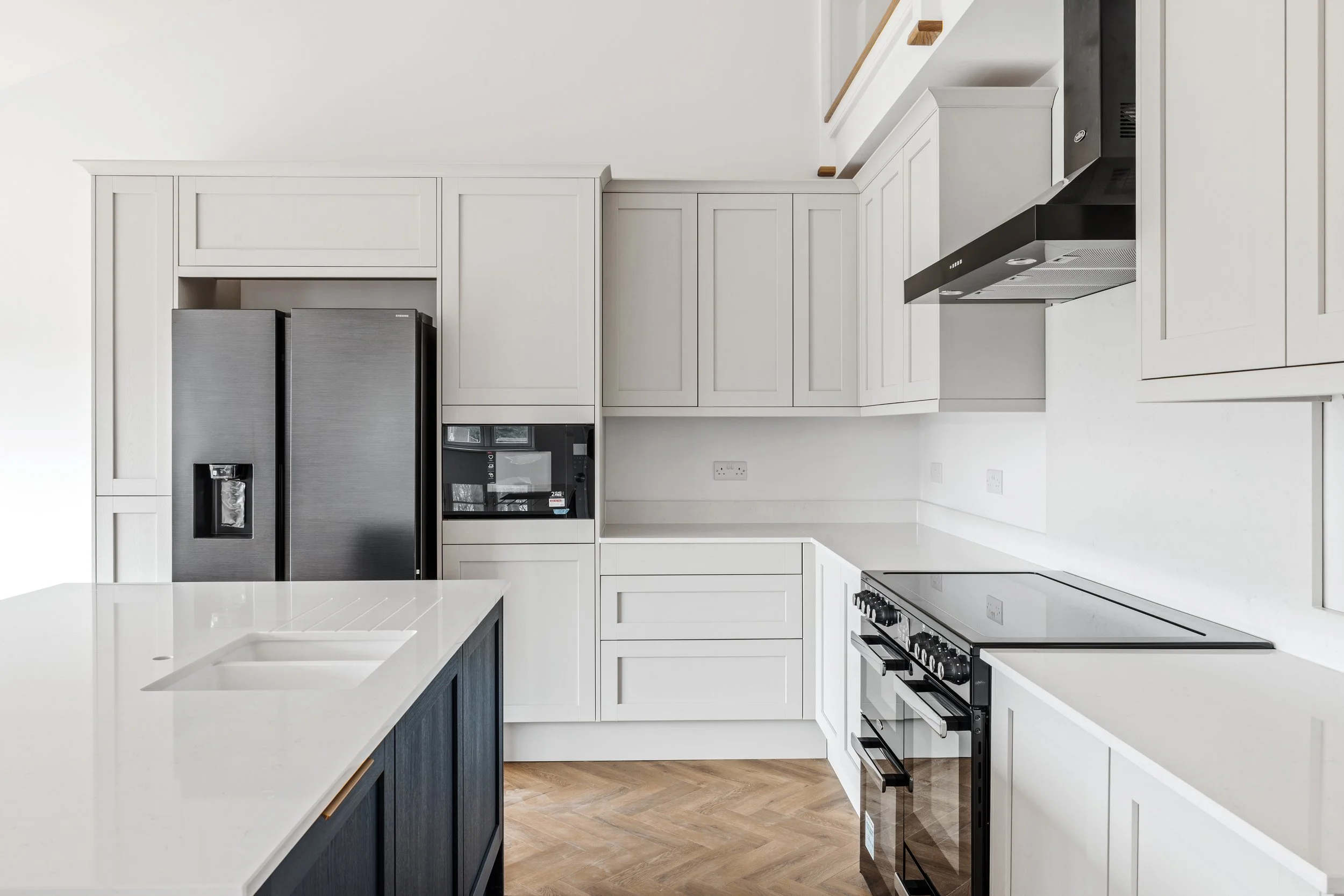 Modern kitchen with white cabinetry, black appliances, and wooden flooring.