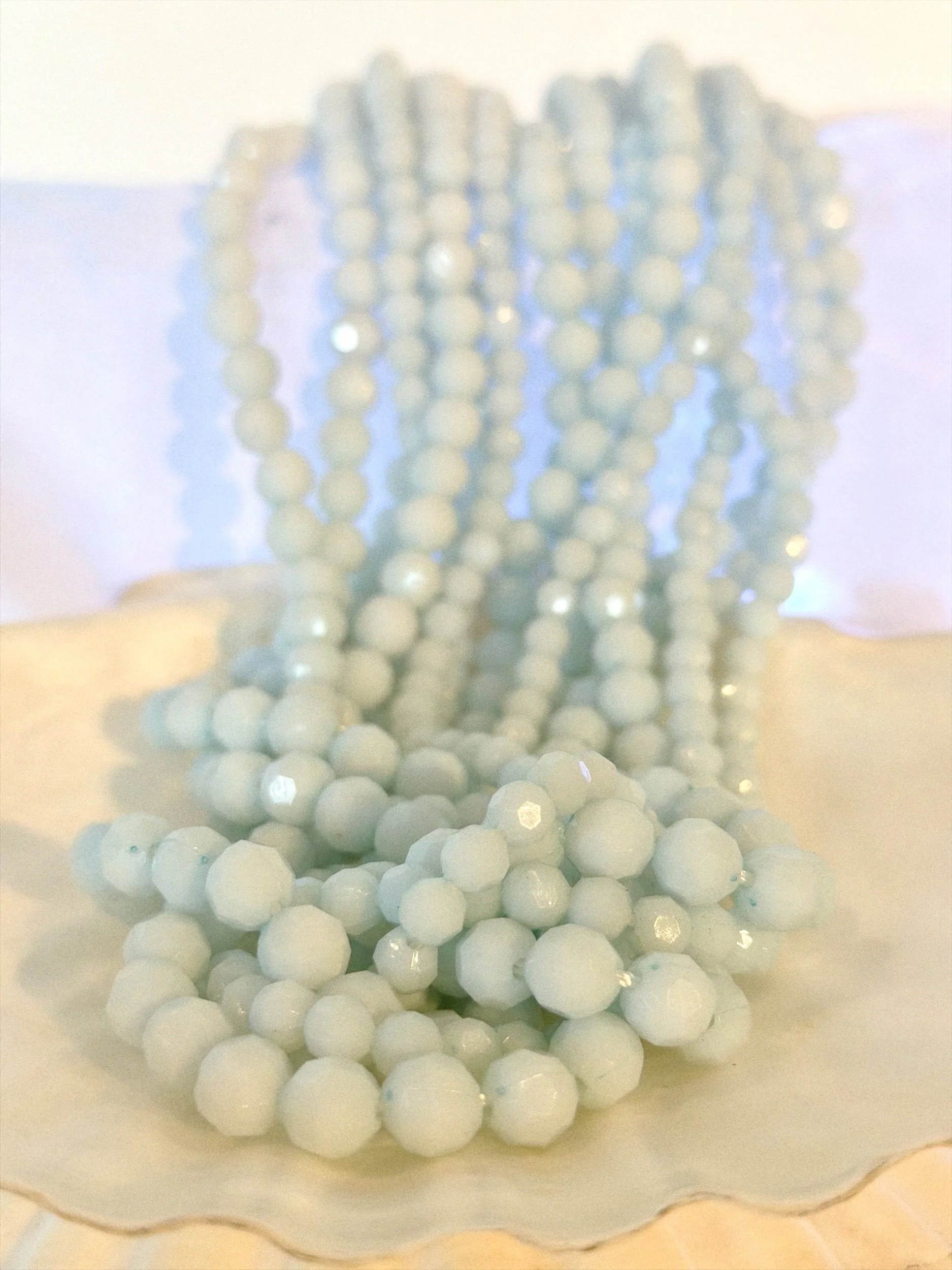 Layered pastel blue bead necklace styled on bare neckline