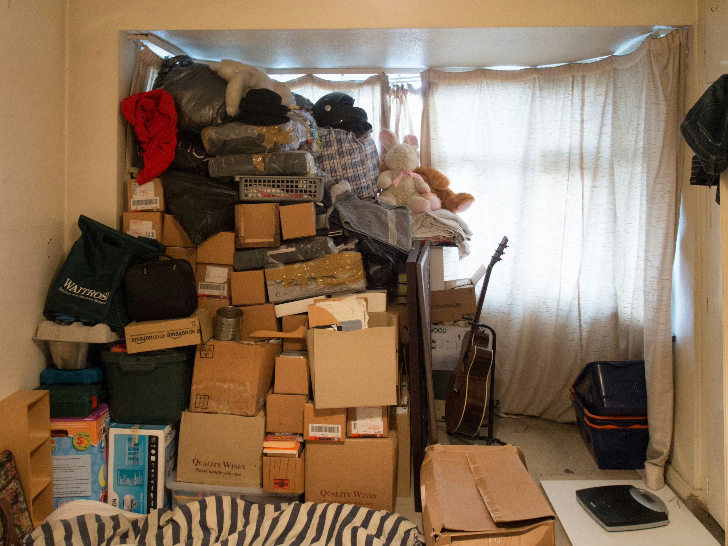 A cluttered room filled with stacked boxes, bags, and lots of other things.