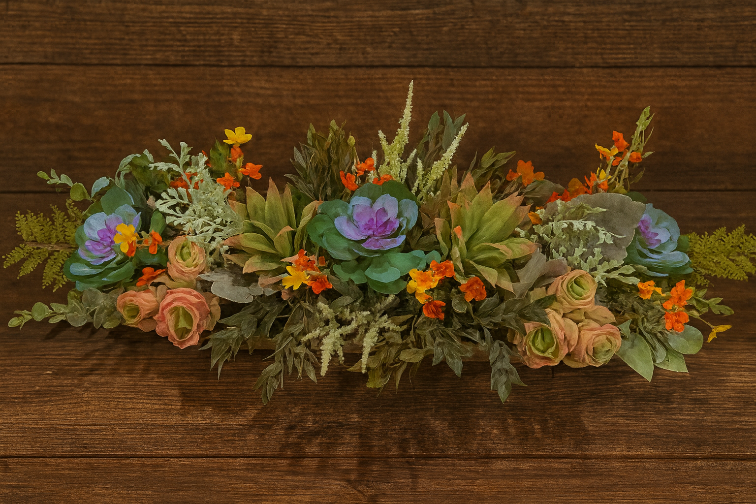 A floral arrangement with purple succulents, pink roses, orange and yellow flowers, and green foliage on a wooden surface.