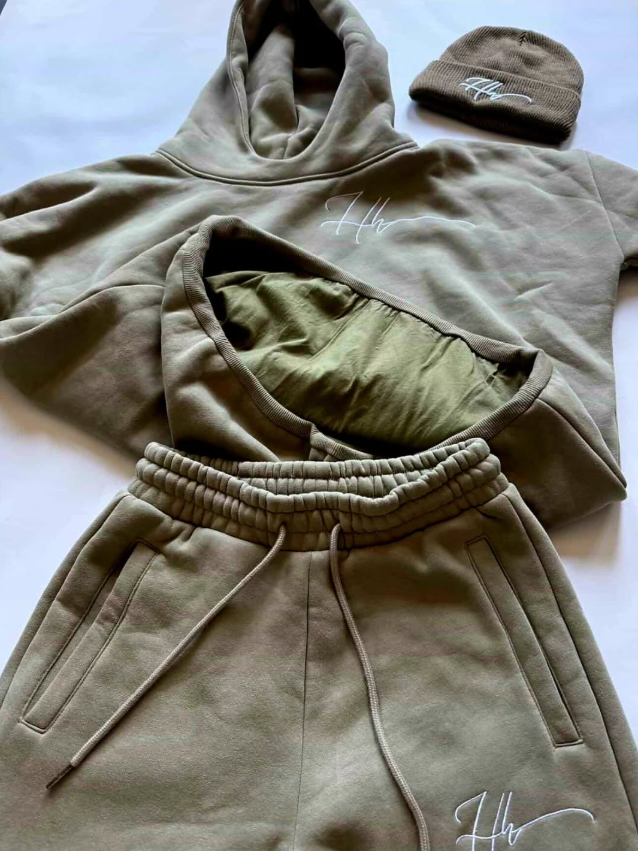 A moss hoodie, matching sweatpants with drawstrings, a moss beanie, and a pair of moss shorts, all laid out flat on a white surface with exposing the double layer design.