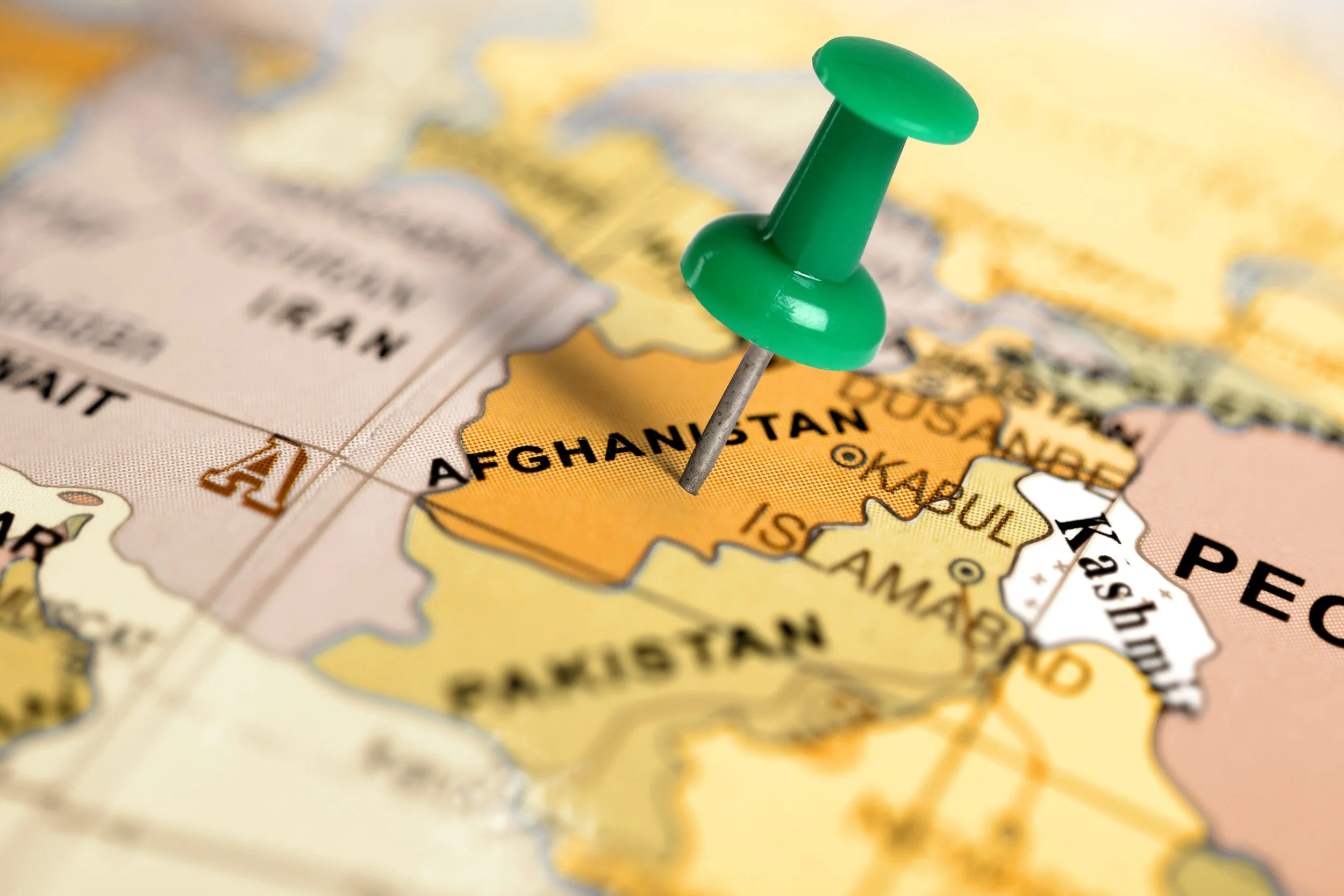 A green pushpin marking Afghanistan on a detailed map of Central Asia.