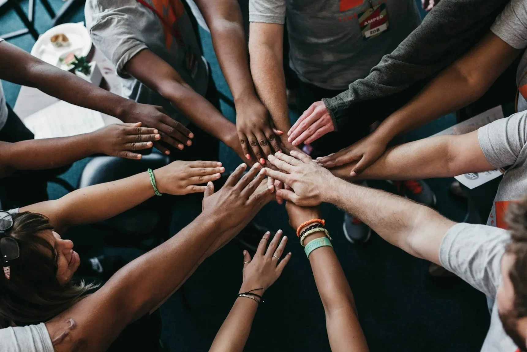 Multiple diverse hands stacked together in a display of unity and teamwork.